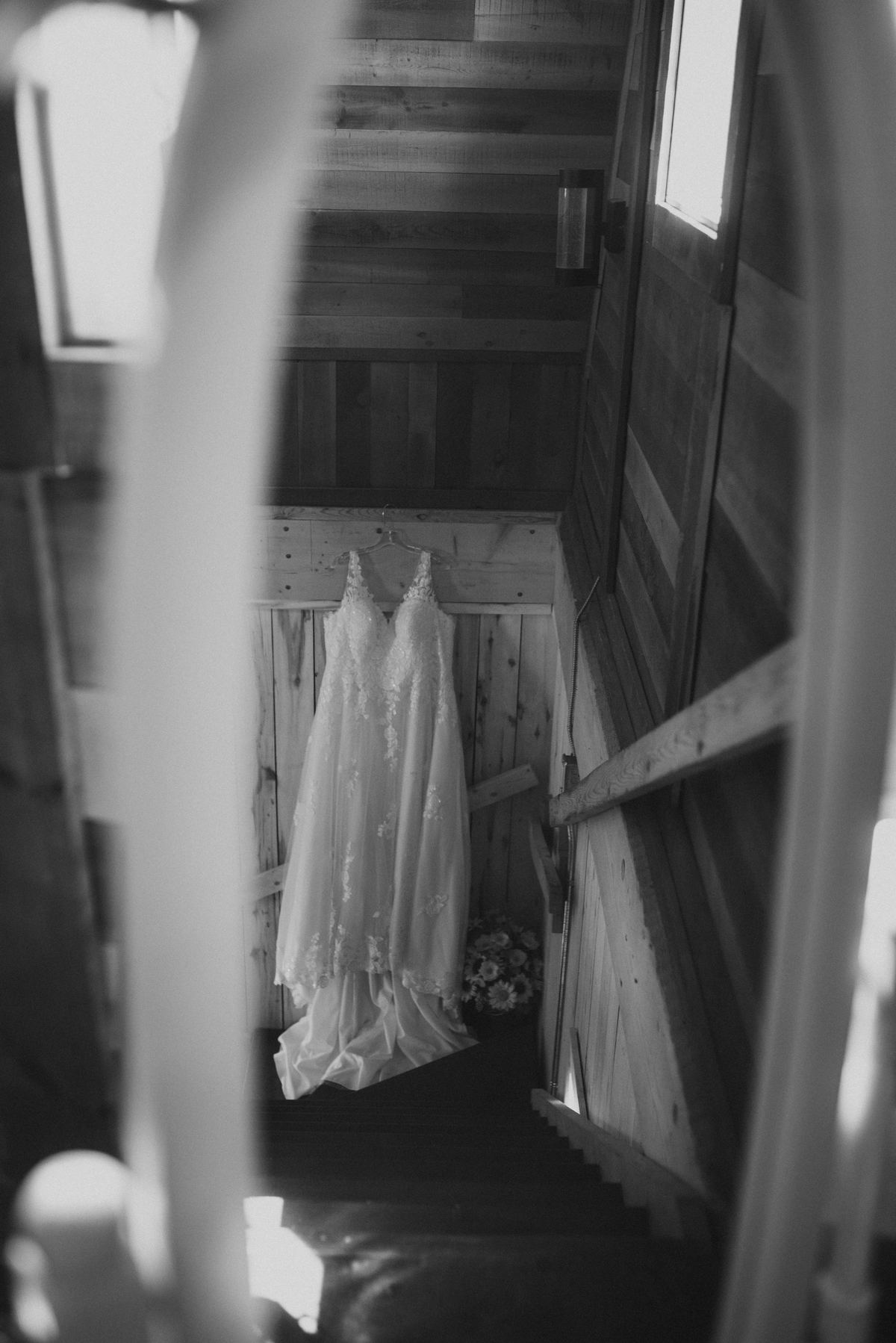 Alysia's white lace bridal gown hanging in the barn stairwell — Deer Meadow Farm wedding Manitoba by Chris Ngo