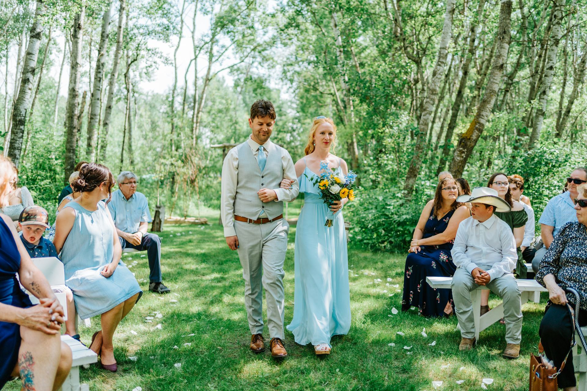 Bridesmaid processional walking the birch forest aisle at Deer Meadow Farm Manitoba wedding