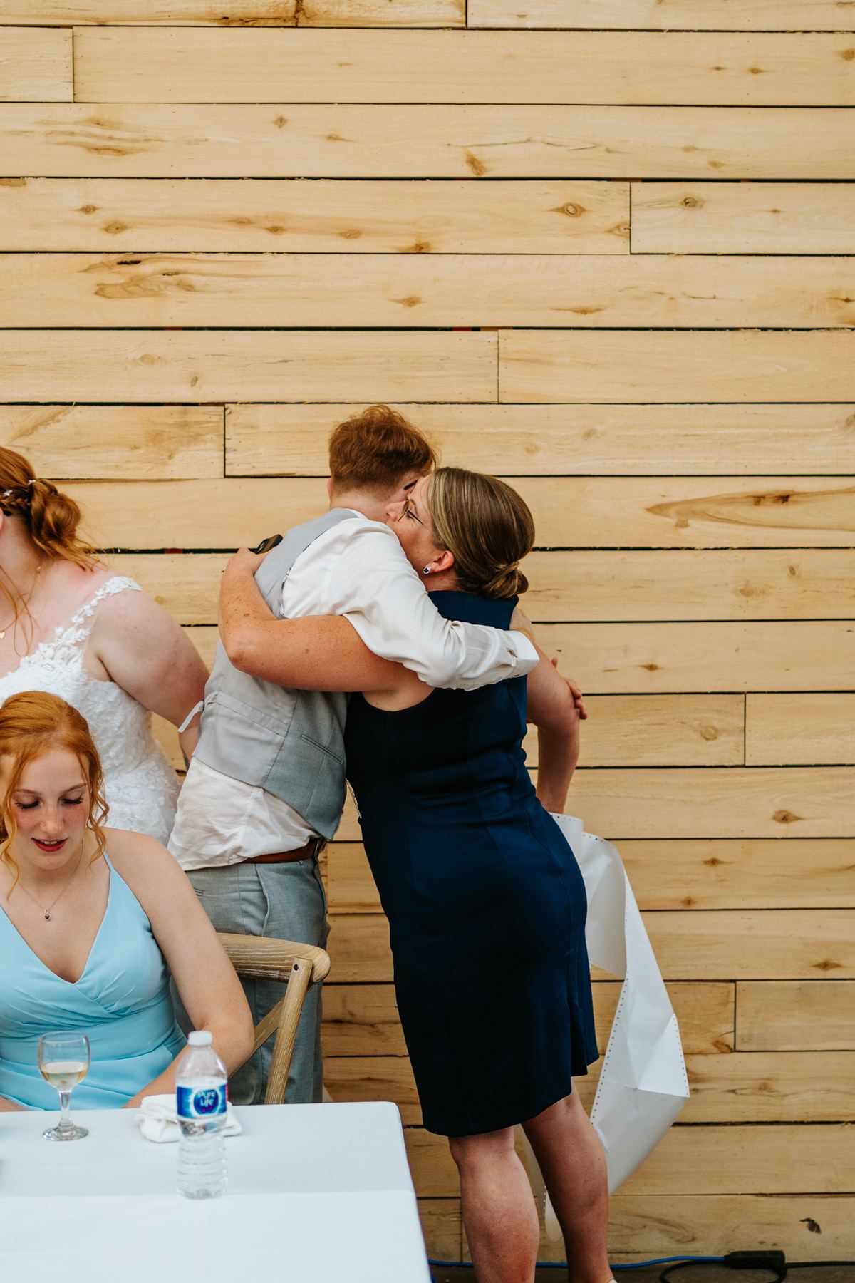 Groom Josh hugging someone after a speech at Deer Meadow Farm reception — Manitoba wedding photographer Chris Ngo