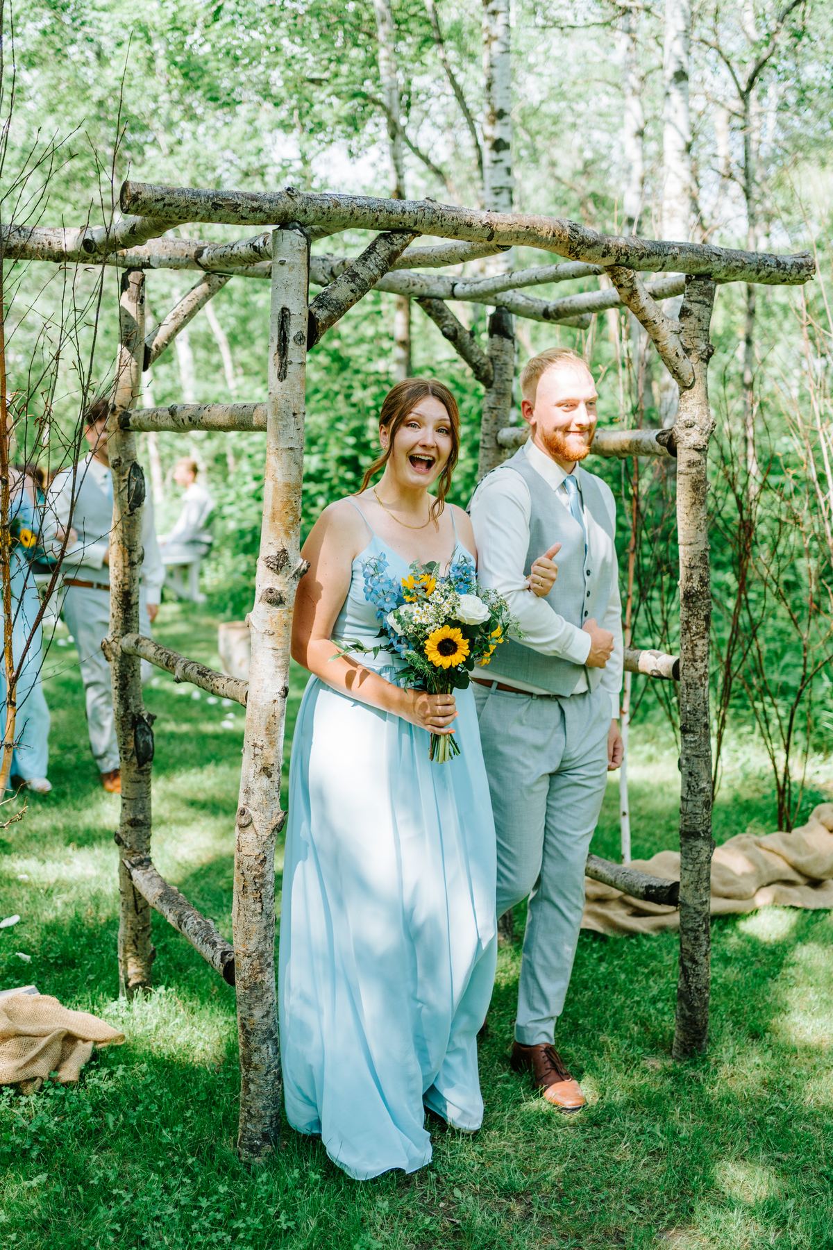 Bridesmaids and groomsmen at the log arbor during recessional at Deer Meadow Farm Manitoba wedding