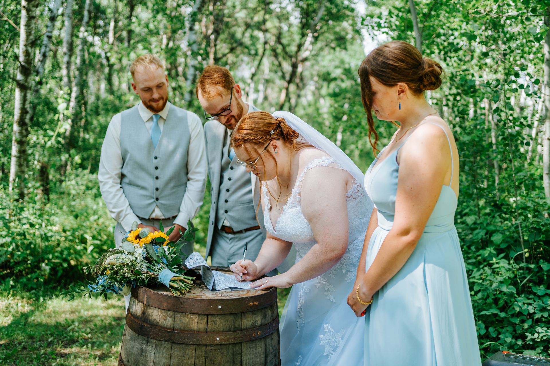 Couple signing the register on a wooden barrel in the birch forest — Deer Meadow Farm Manitoba wedding