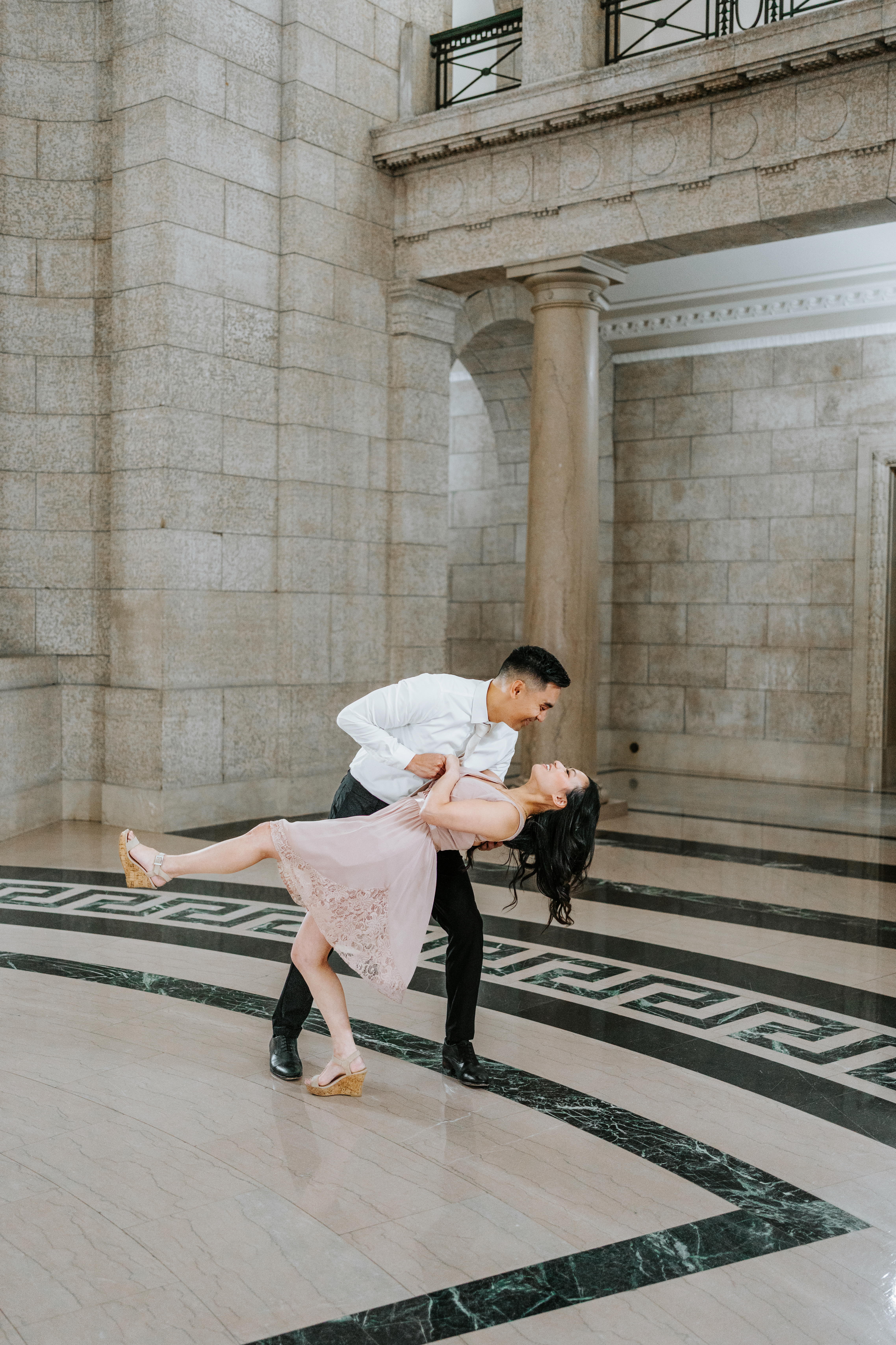 AJ dipping Julie on the Greek key marble floor of the Manitoba Legislative Building Winnipeg — engagement photography by Ngo Photography