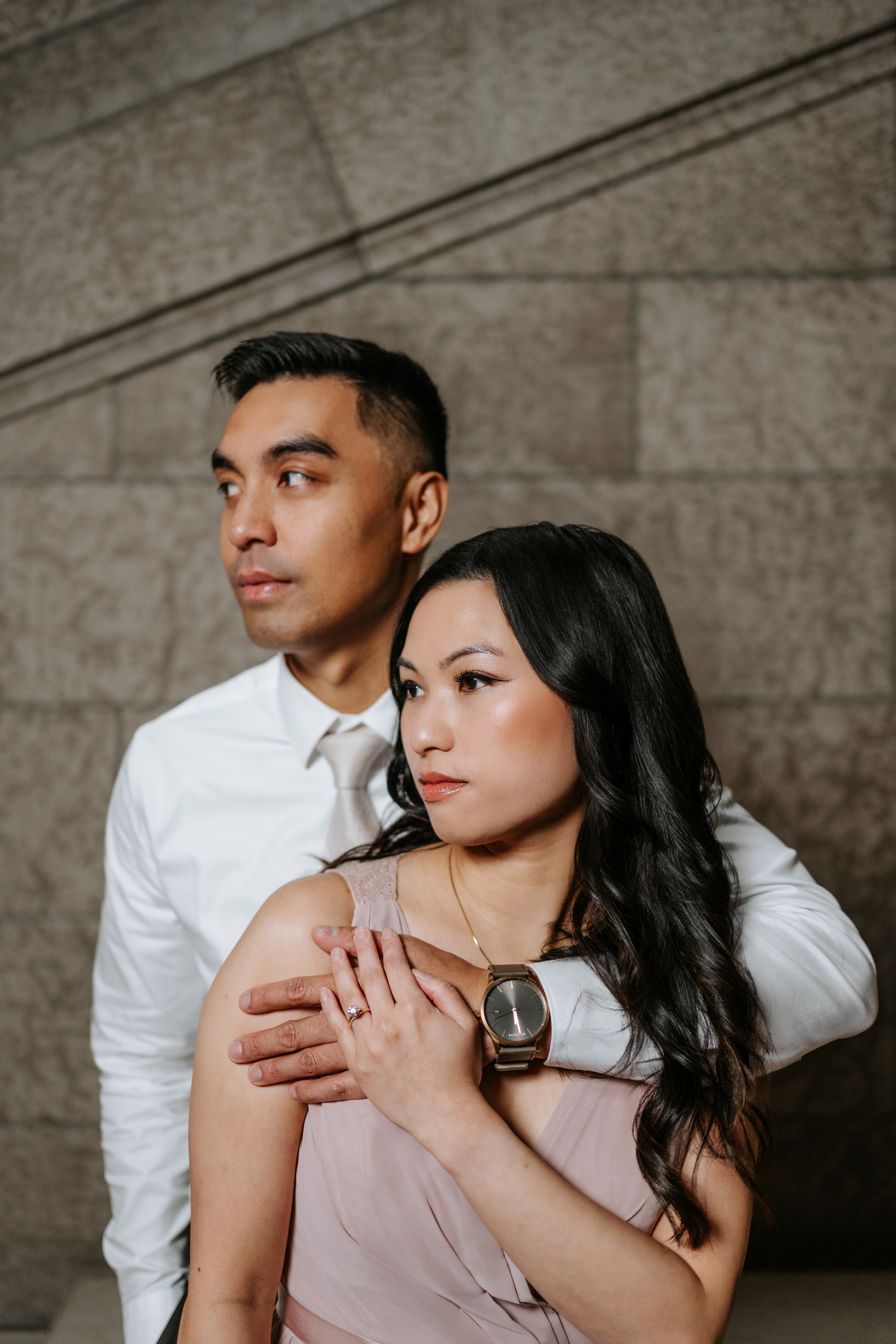 Editorial close-up engagement portrait of AJ and Julie against the warm limestone wall at the Manitoba Legislative Building Winnipeg — Ngo Photography