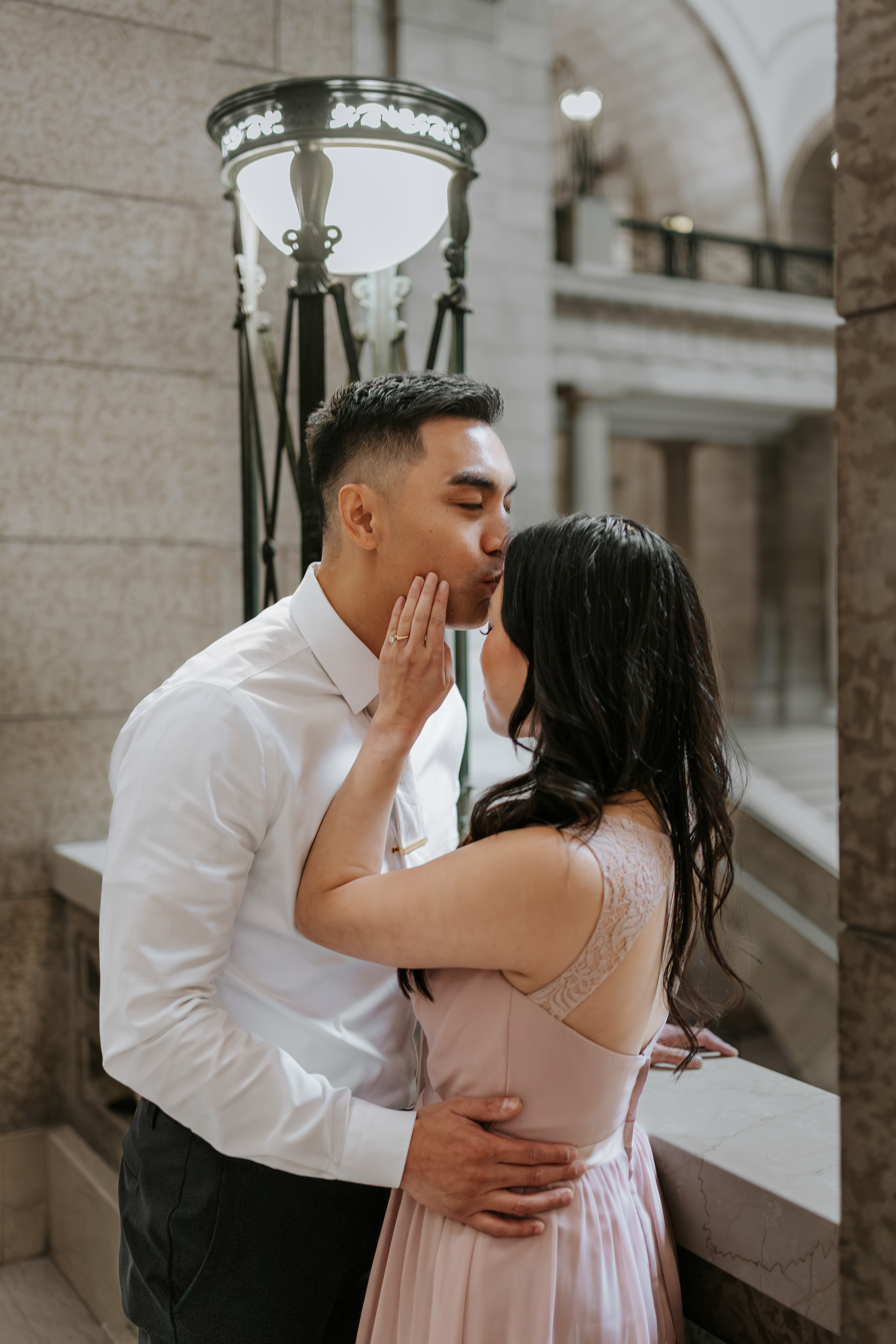 AJ and Julie kissing beside an ornate iron lantern on the upper level of the Manitoba Legislative Building Winnipeg — engagement session by Chris Ngo