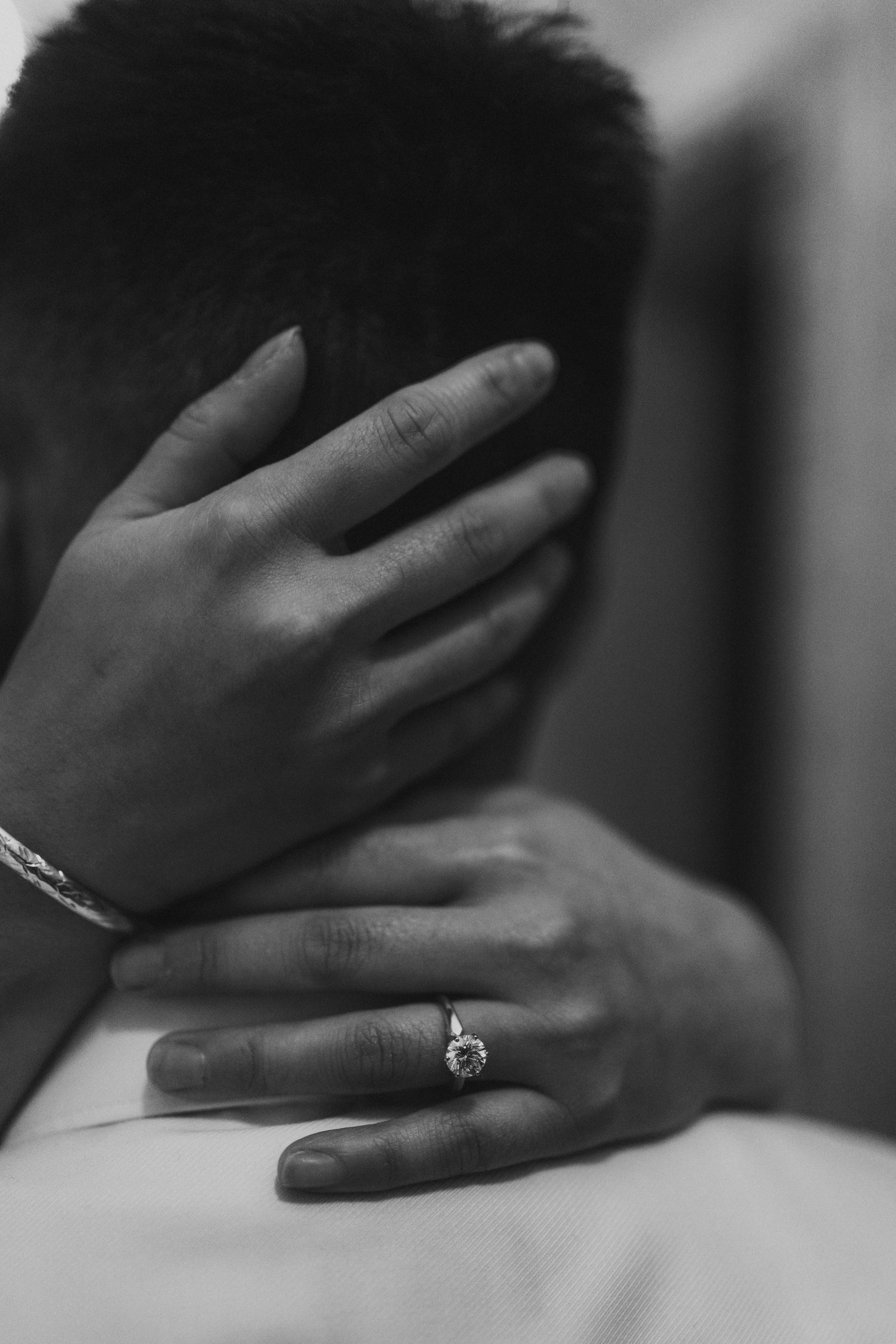 Black and white detail of Julie's engagement ring on AJ's back as they embrace — engagement ring photography by Ngo Photography Winnipeg