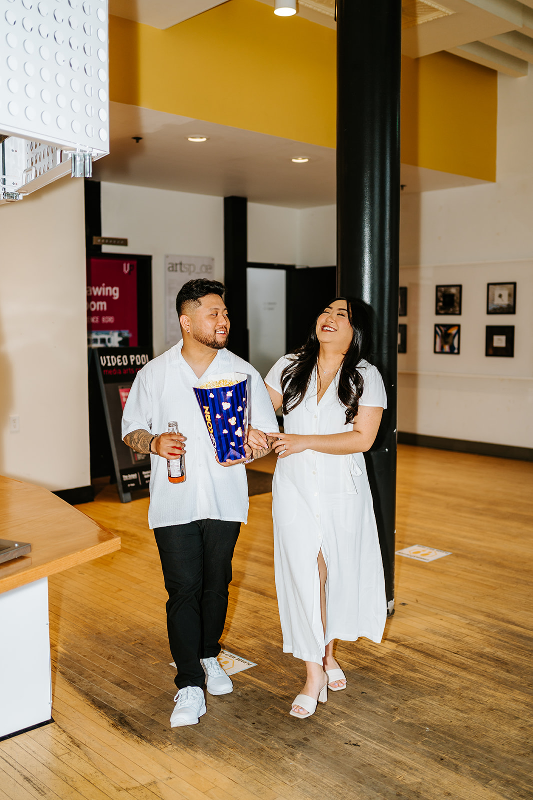 Ayanna and Paul walking laughing theatre lobby engagement Winnipeg — Ngo Photography