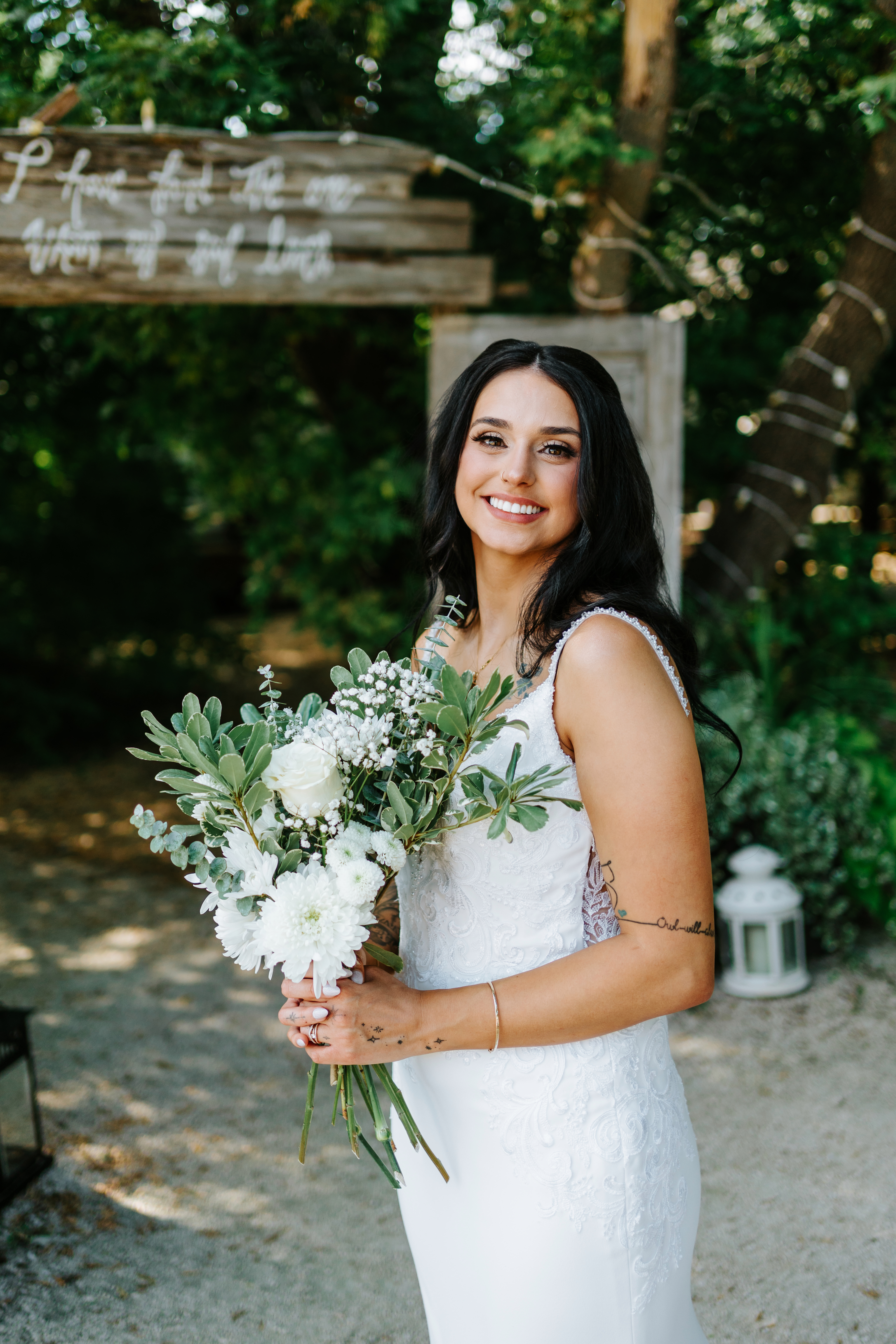 Selena smiling at the Ashgrove Acres venue entrance sign on her wedding day — Manitoba wedding photography by Chris Ngo