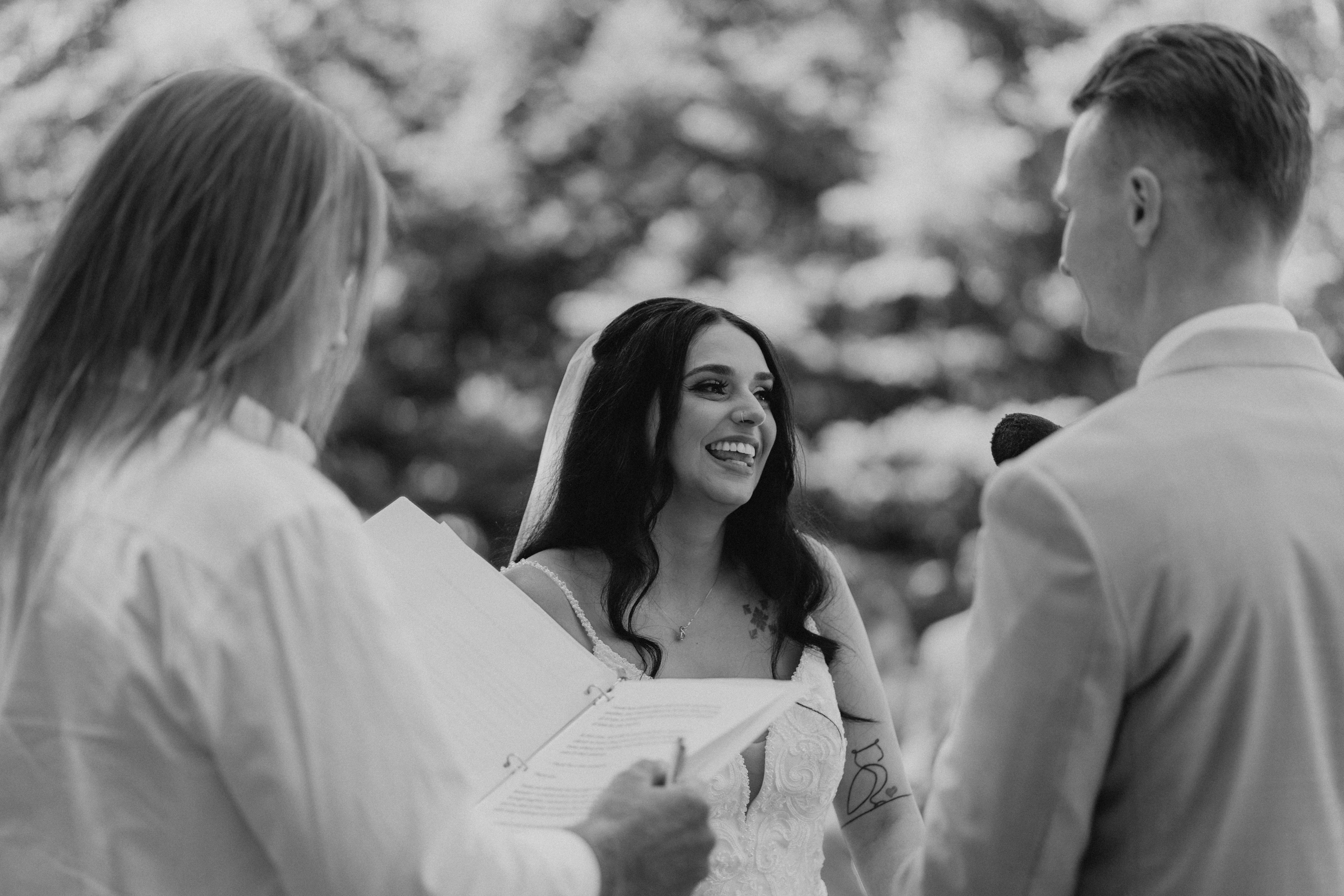 Selena smiling during her wedding vows at Ashgrove Acres outdoor ceremony — black and white wedding photography by Ngo Photography