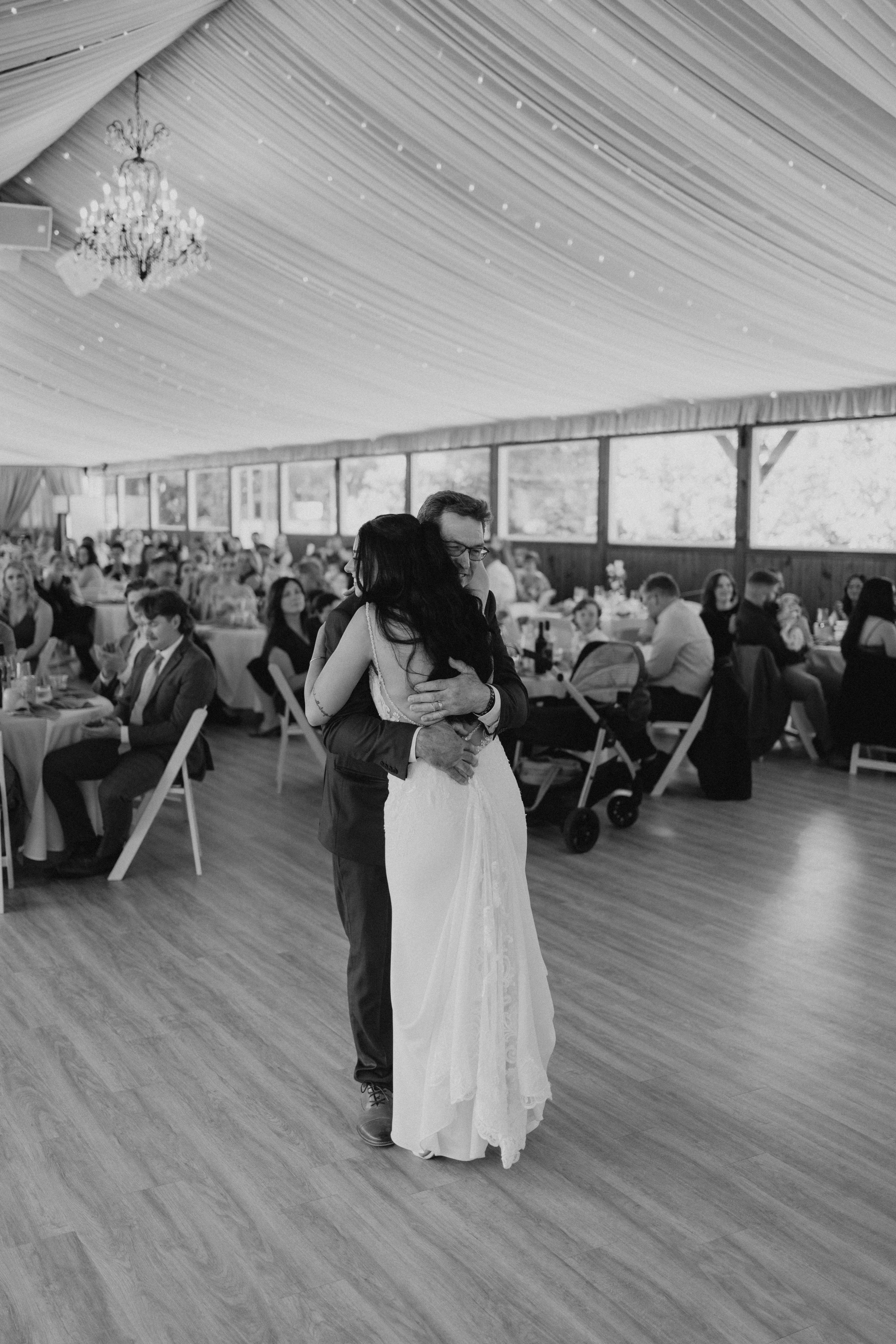 Brandon and Selena first dance under chandelier at Ashgrove Acres tented reception — black and white wedding photography Winnipeg