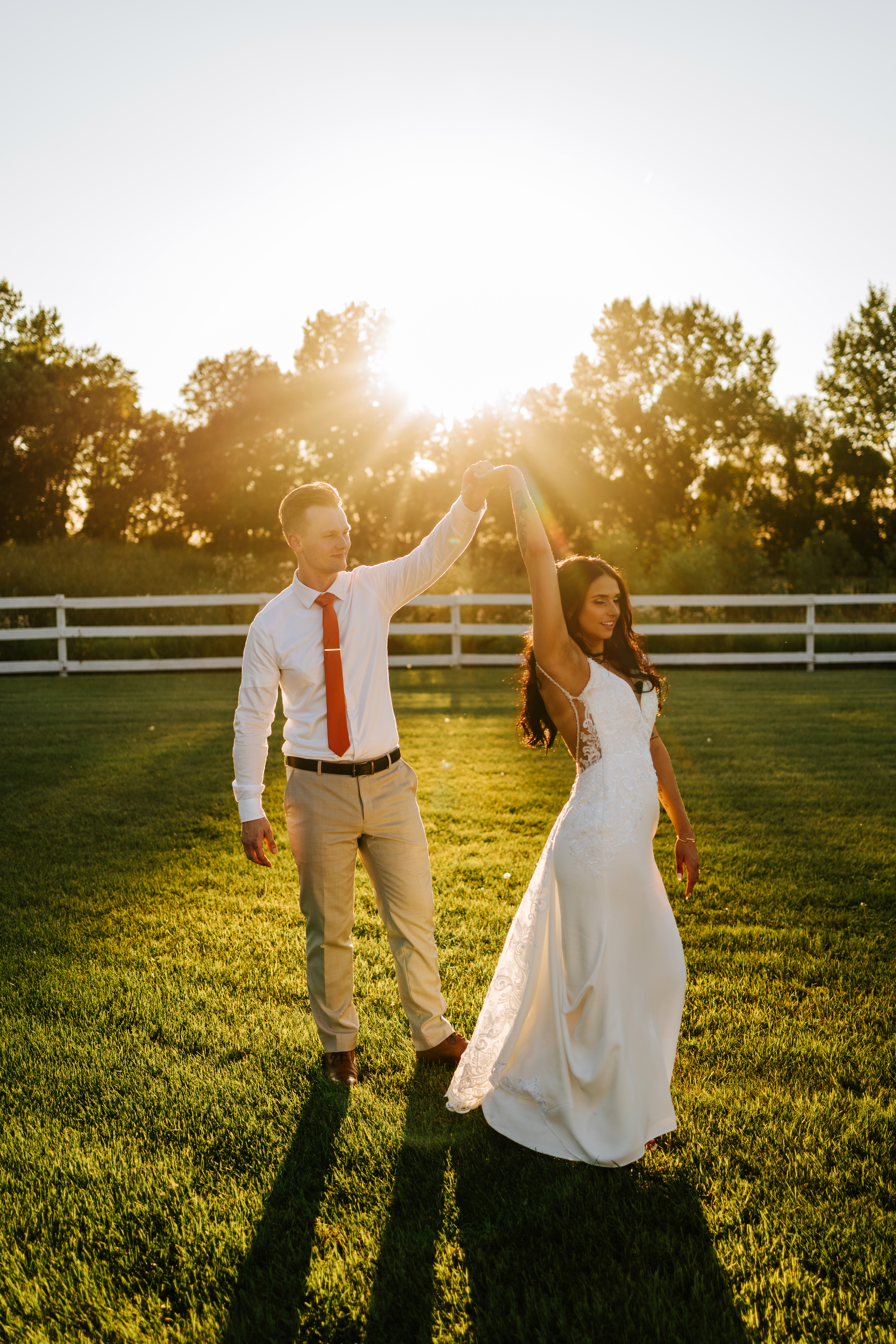 Brandon and Selena golden hour couple twirl with sun flare at Ashgrove Acres white fence — Winnipeg wedding photographer Chris Ngo, Ngo Photography