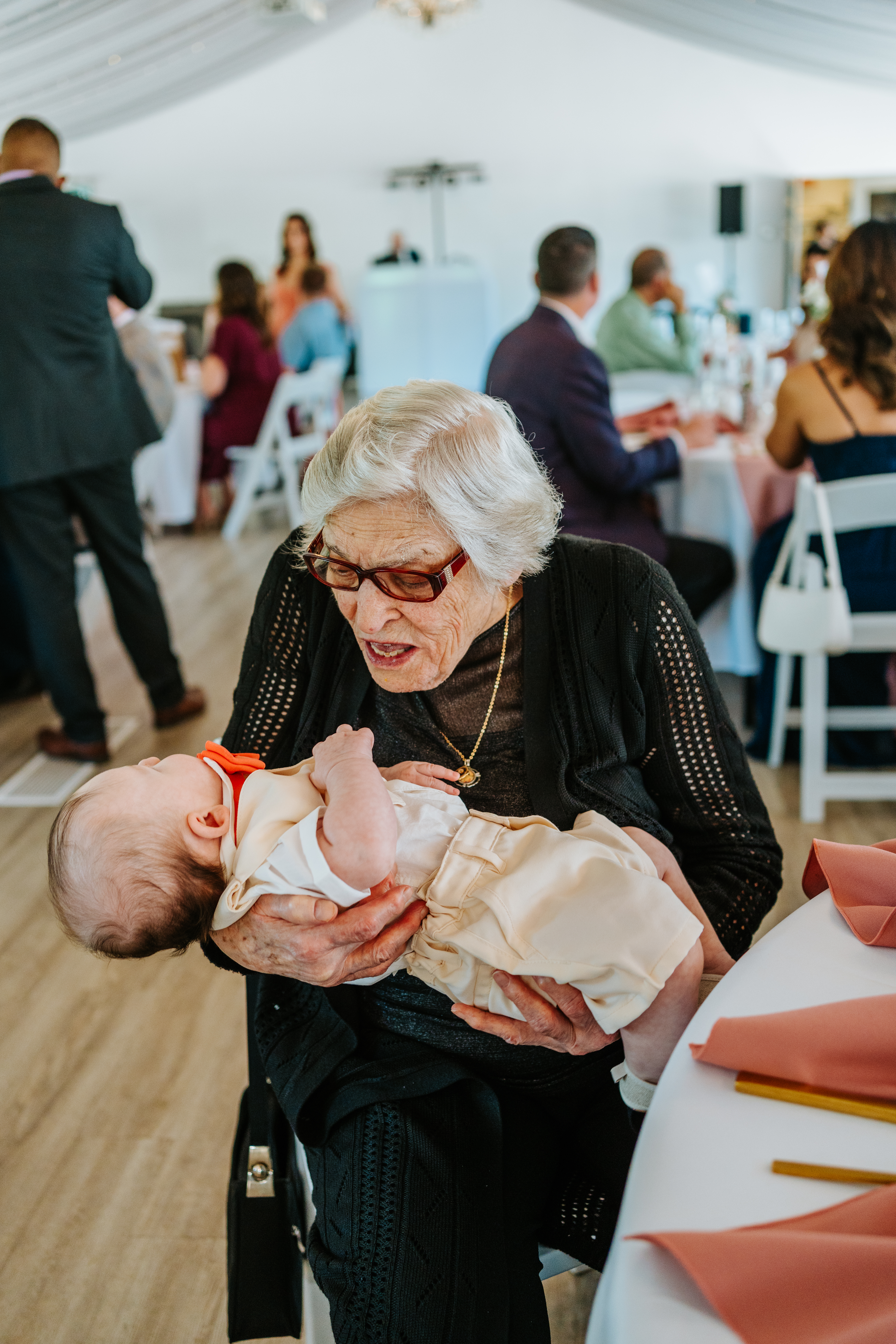 Grandmother holding baby at Brandon and Selena's Ashgrove Acres reception — candid wedding photography by Ngo Photography