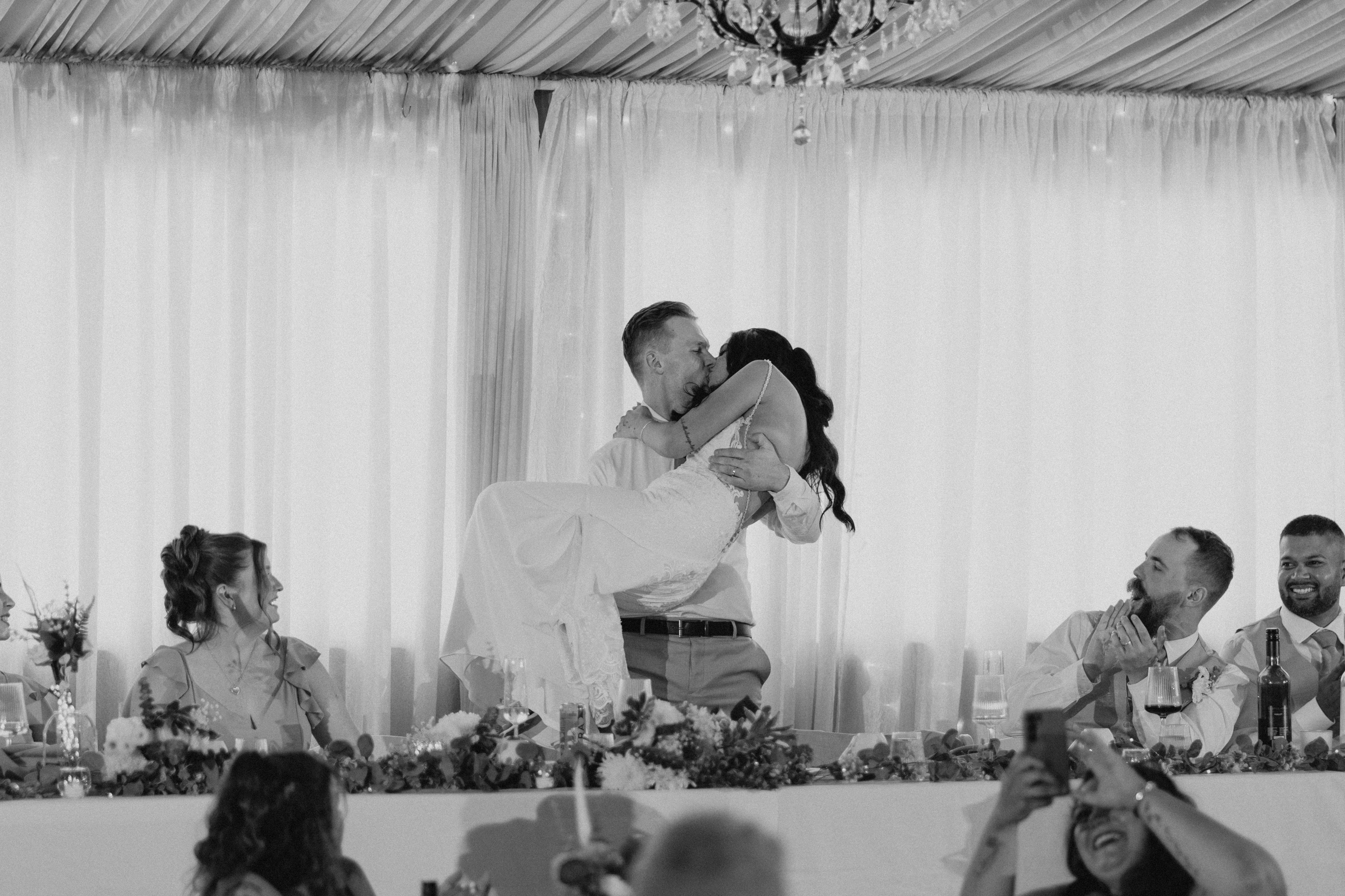 Groom lifting bride in a kiss at Ashgrove Acres wedding reception — black and white wedding photography by Ngo Photography Winnipeg