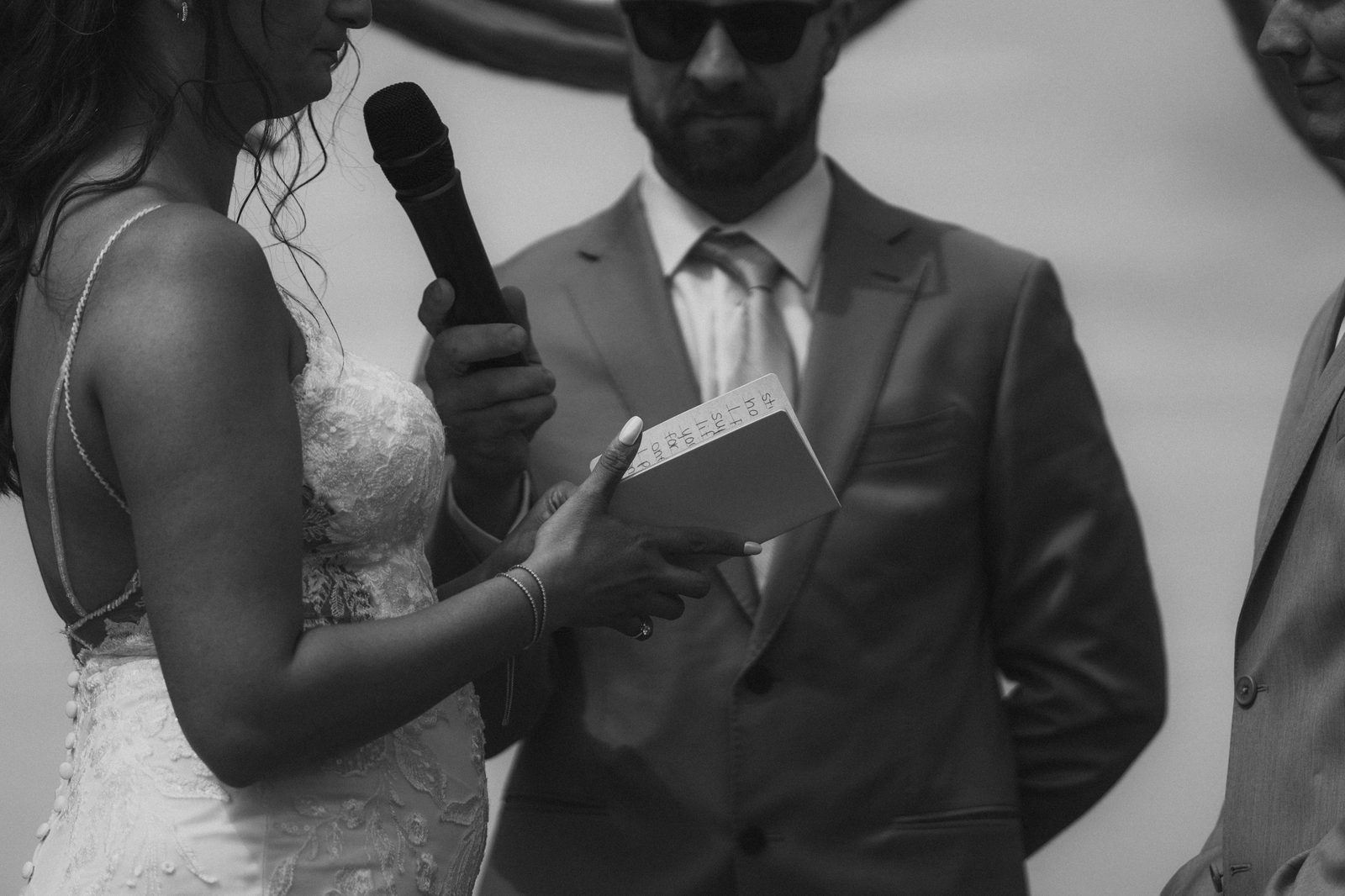 Bride Christina reading personal vows from a notebook at the microphone, black and white — Pelican Yacht Club wedding, Ninette, Manitoba