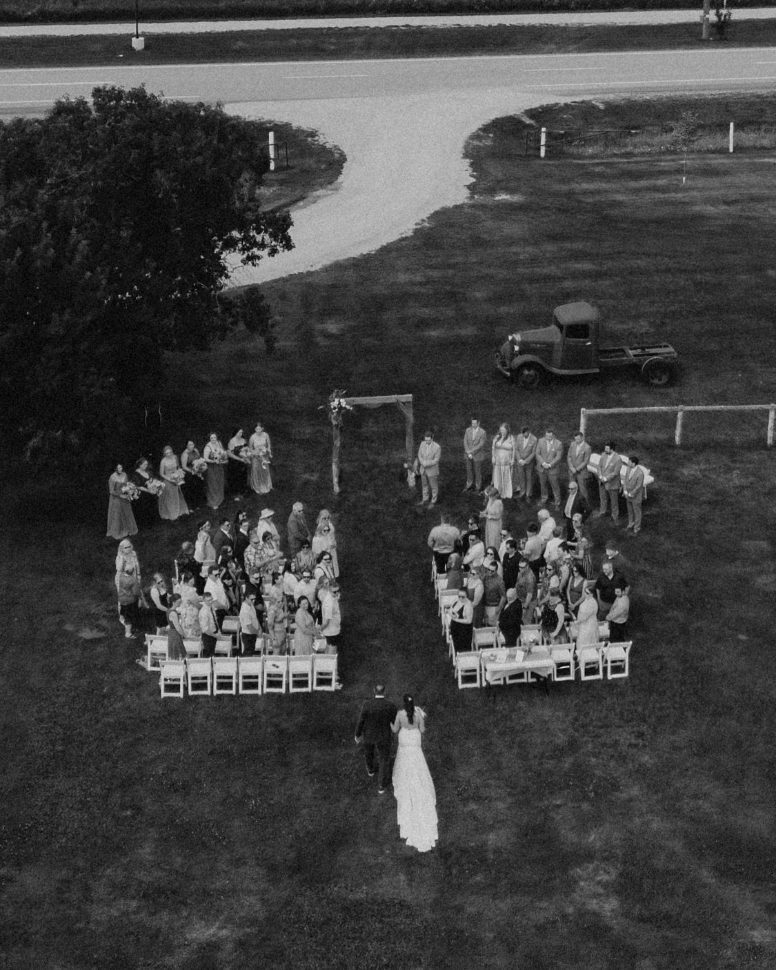 Aerial drone view of the ceremony at Pelican Yacht Club — wedding party and guests visible from above, Pelican Lake in the background — Ninette, Manitoba