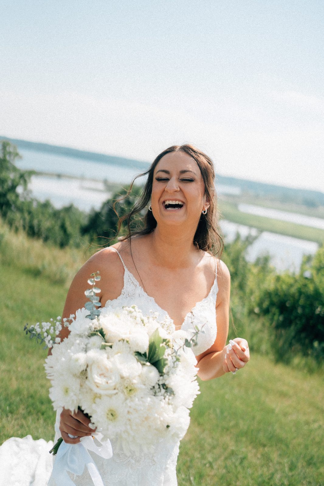Bride Christina laughing on the hilltop with Pelican Lake behind her, film-toned — Pelican Yacht Club, Ninette, Manitoba