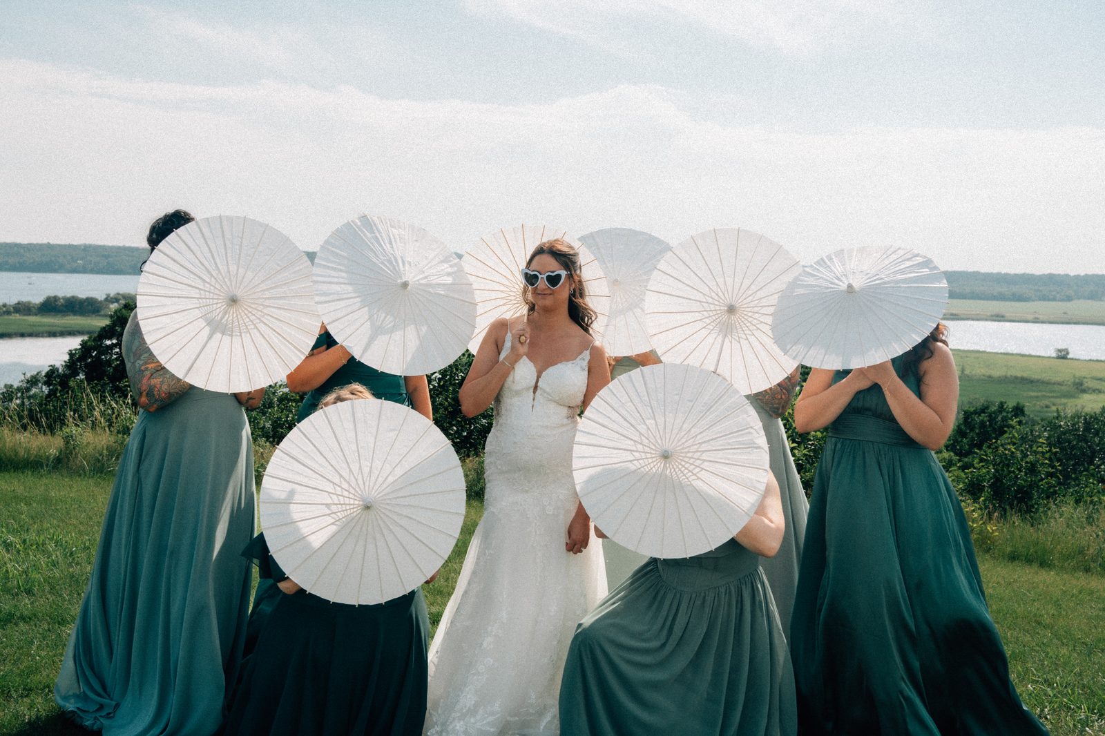Film-toned parasol and heart sunglasses group portrait on the hillside above Pelican Lake — Pelican Yacht Club wedding, Ninette, Manitoba