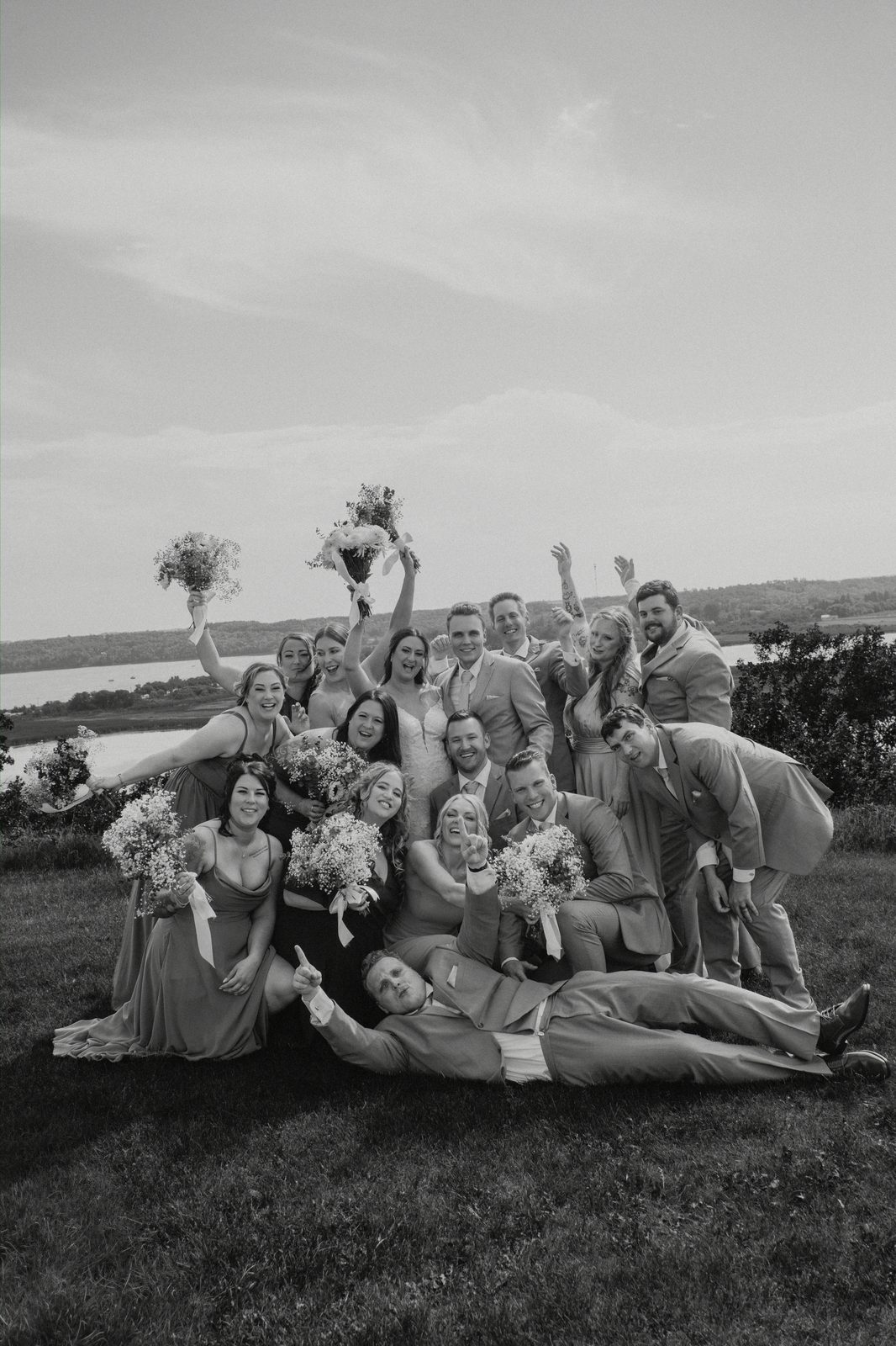 Full wedding party black and white group portrait on the hilltop at Pelican Yacht Club — Pelican Lake spanning the background — Ninette, Manitoba wedding photography by Chris Ngo