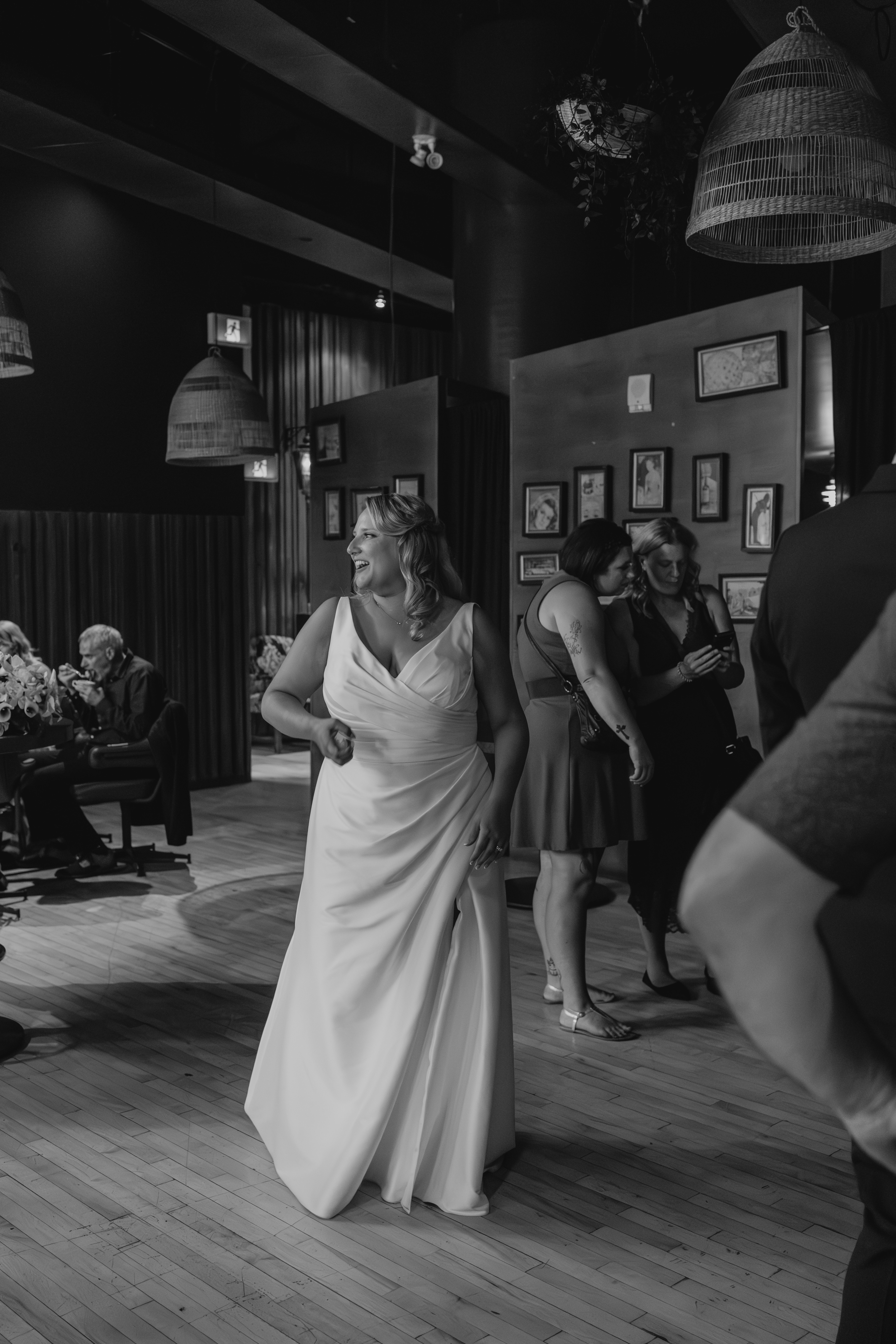 Bailey dancing on the reception floor at Rudy's restaurant, mid-movement in her wedding gown with guests behind her — documentary wedding photography by Ngo Photography Winnipeg