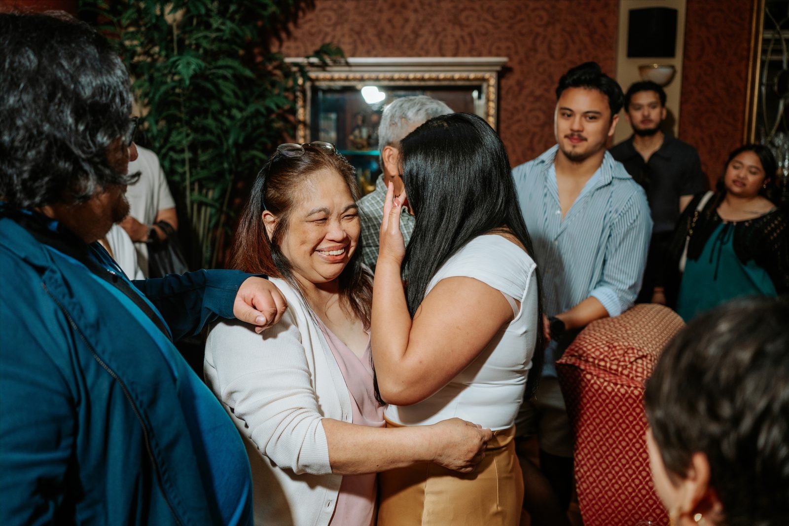 Deril watching as Annie is surrounded by family and friends after the surprise proposal — downtown Winnipeg proposal photographer Chris Ngo