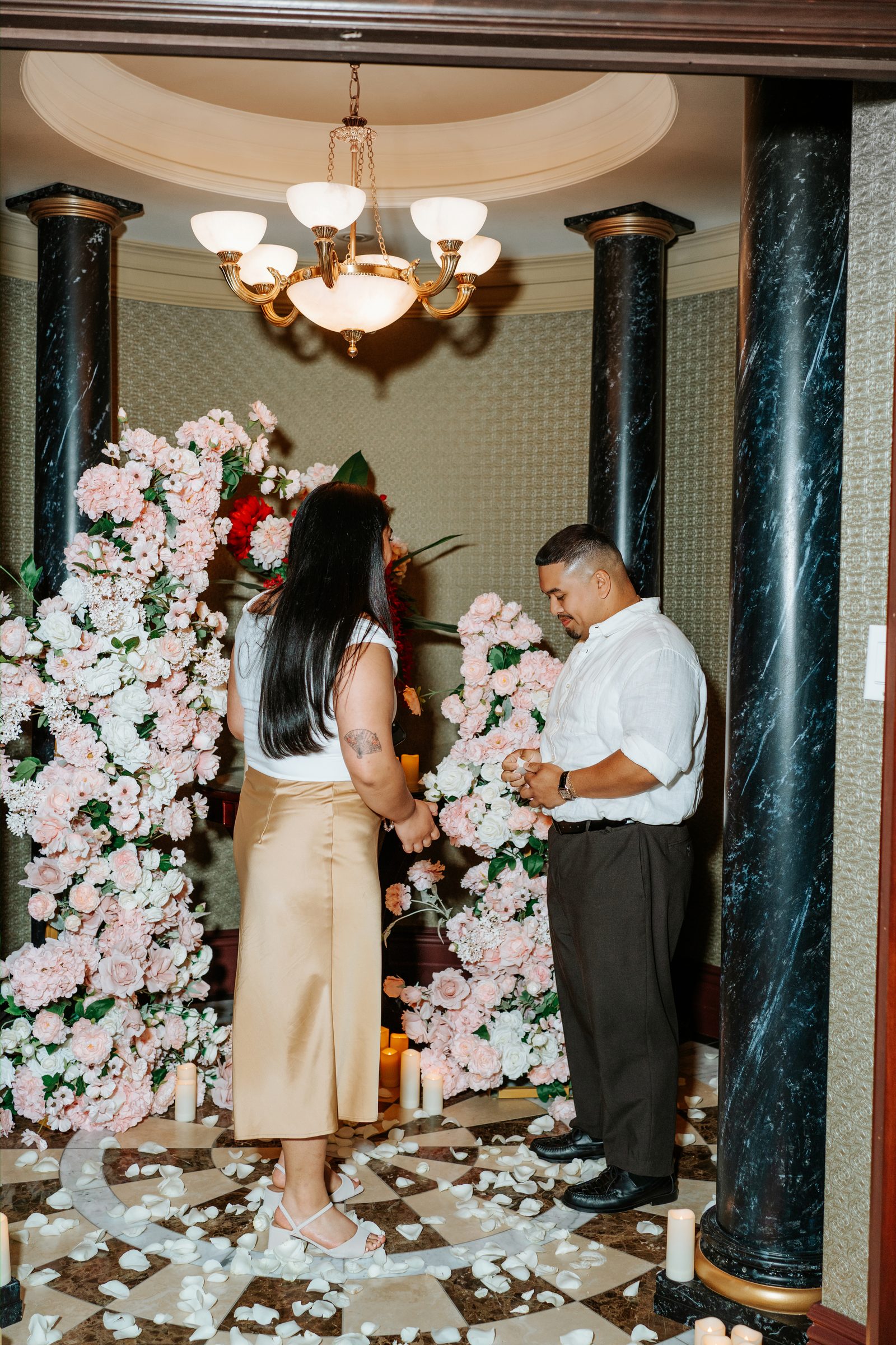 Deril and Annie at the proposal arch — the moment just before Deril gets on one knee — surprise proposal photography in downtown Winnipeg by Ngo Photography