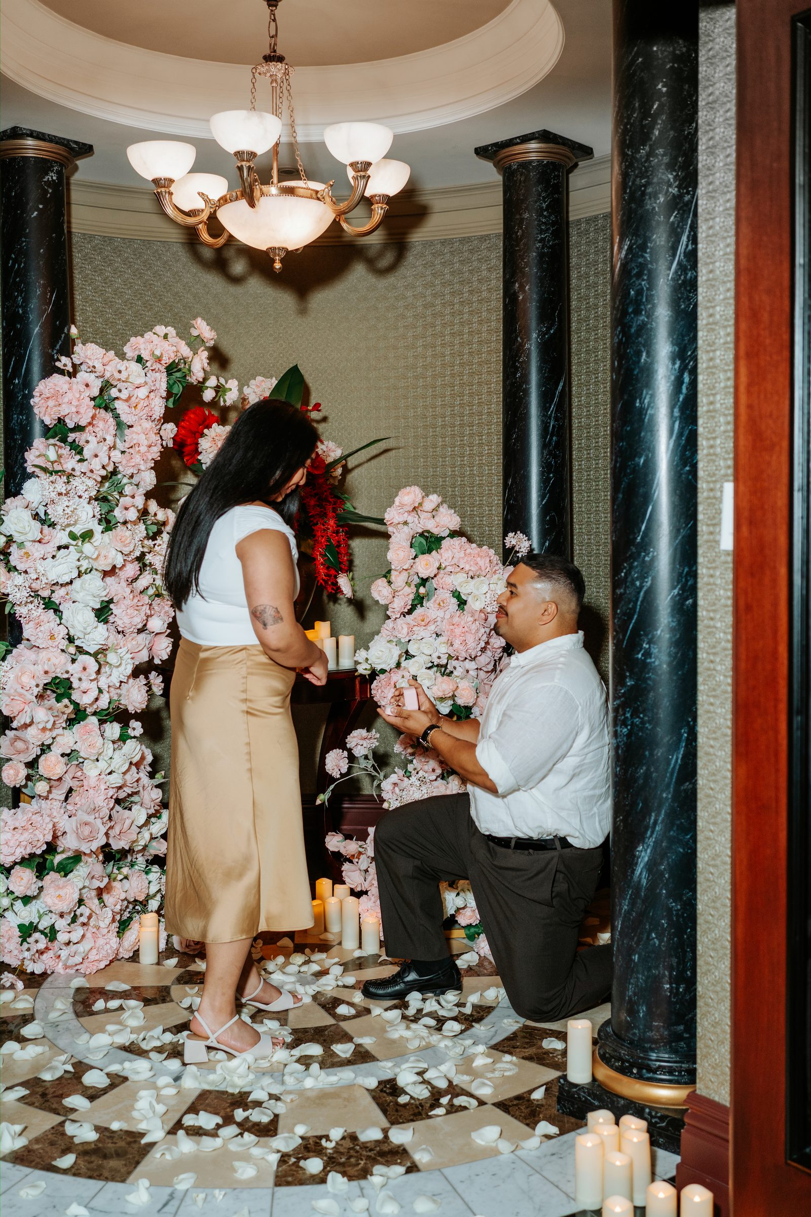 Annie holding Deril's face after the proposal — first engaged portrait with floral arch in the background — surprise proposal photographer Winnipeg by Ngo Photography