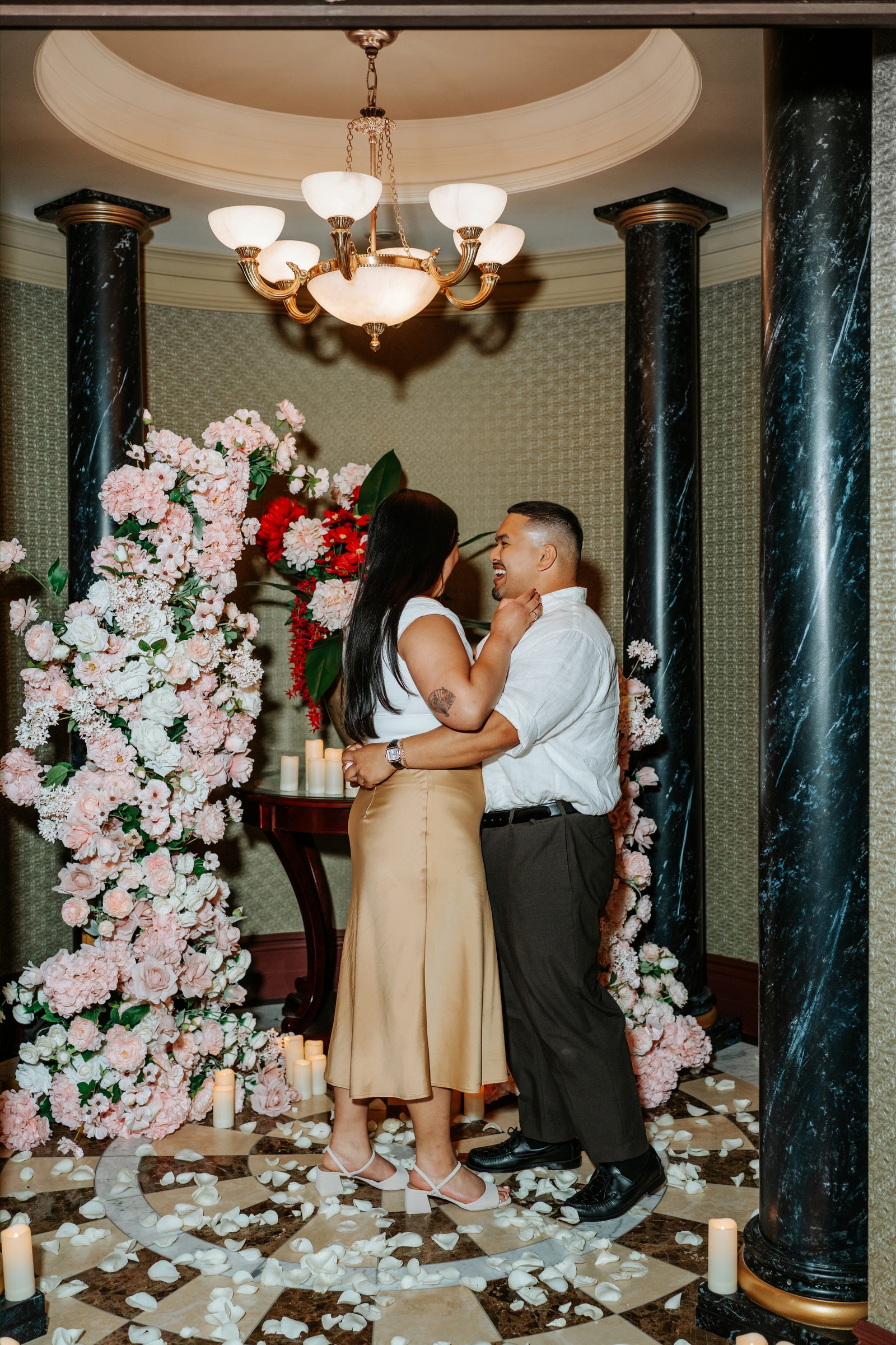 Deril and Annie laughing together in front of the proposal floral arch — downtown Winnipeg proposal photographer Chris Ngo