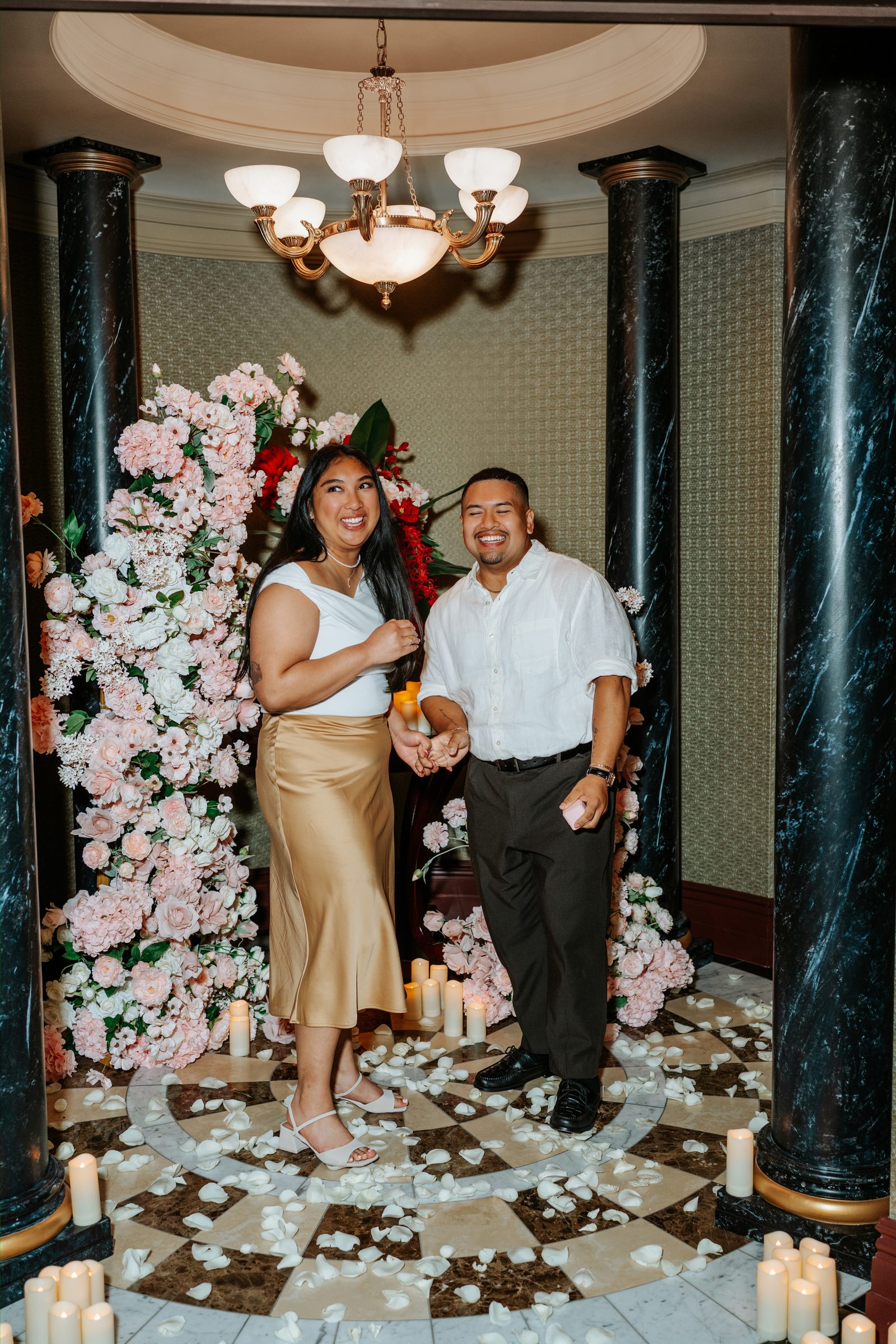 Annie and Deril close — just engaged — with the blush floral arches and candles in the background — surprise proposal photography Winnipeg by Ngo Photography