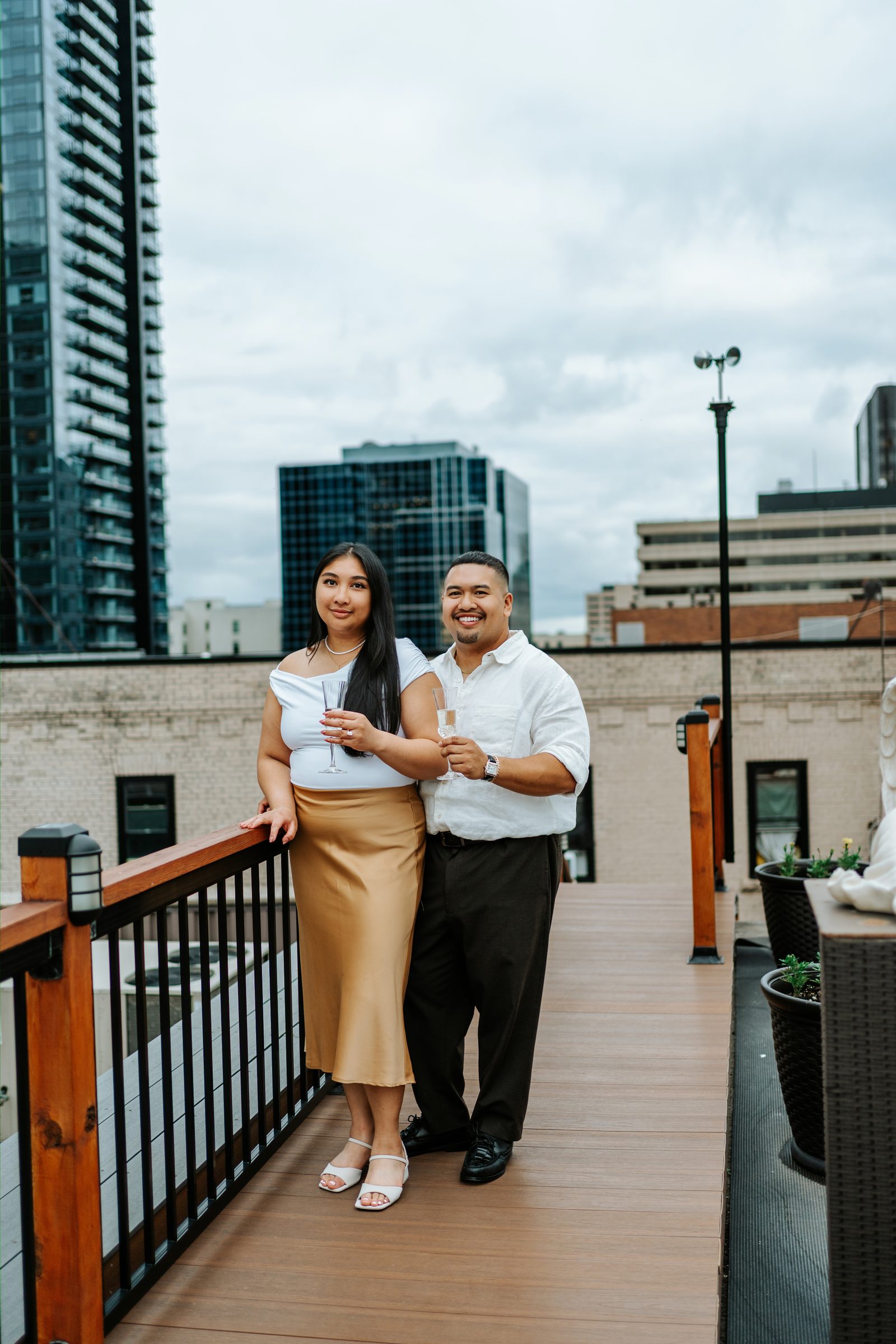 Deril and Annie dancing on the rooftop of a private downtown Winnipeg space — just engaged — surprise proposal photography by Ngo Photography