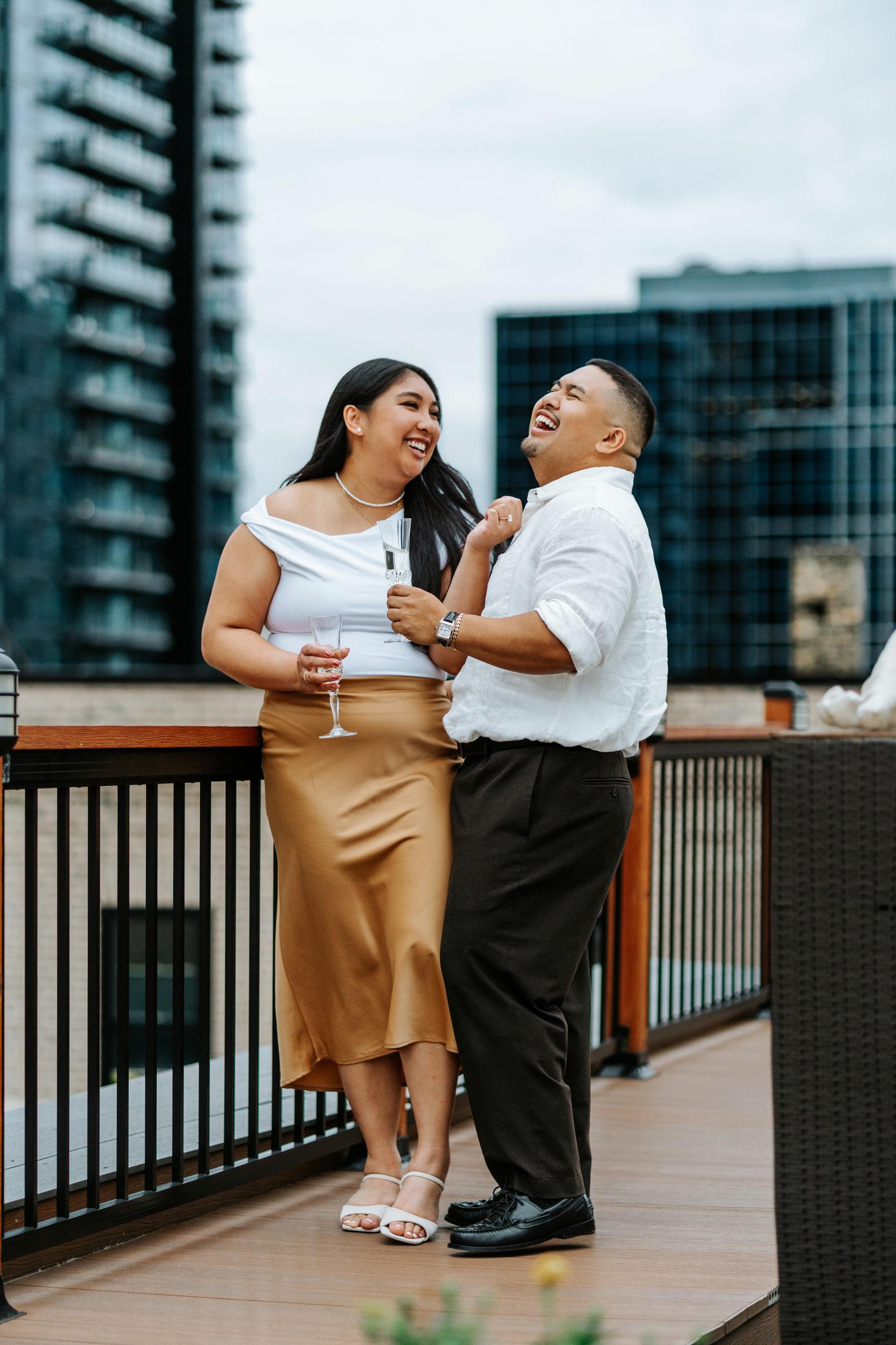Annie and Deril intimate portrait on the rooftop terrace — downtown Winnipeg skyline behind them — surprise proposal photography by Ngo Photography