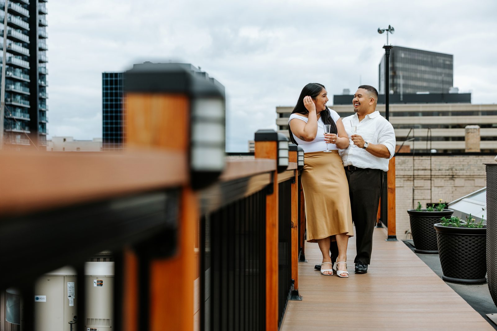 Annie and Deril rooftop portrait with the downtown Winnipeg skyline — just engaged — proposal photography by Ngo Photography