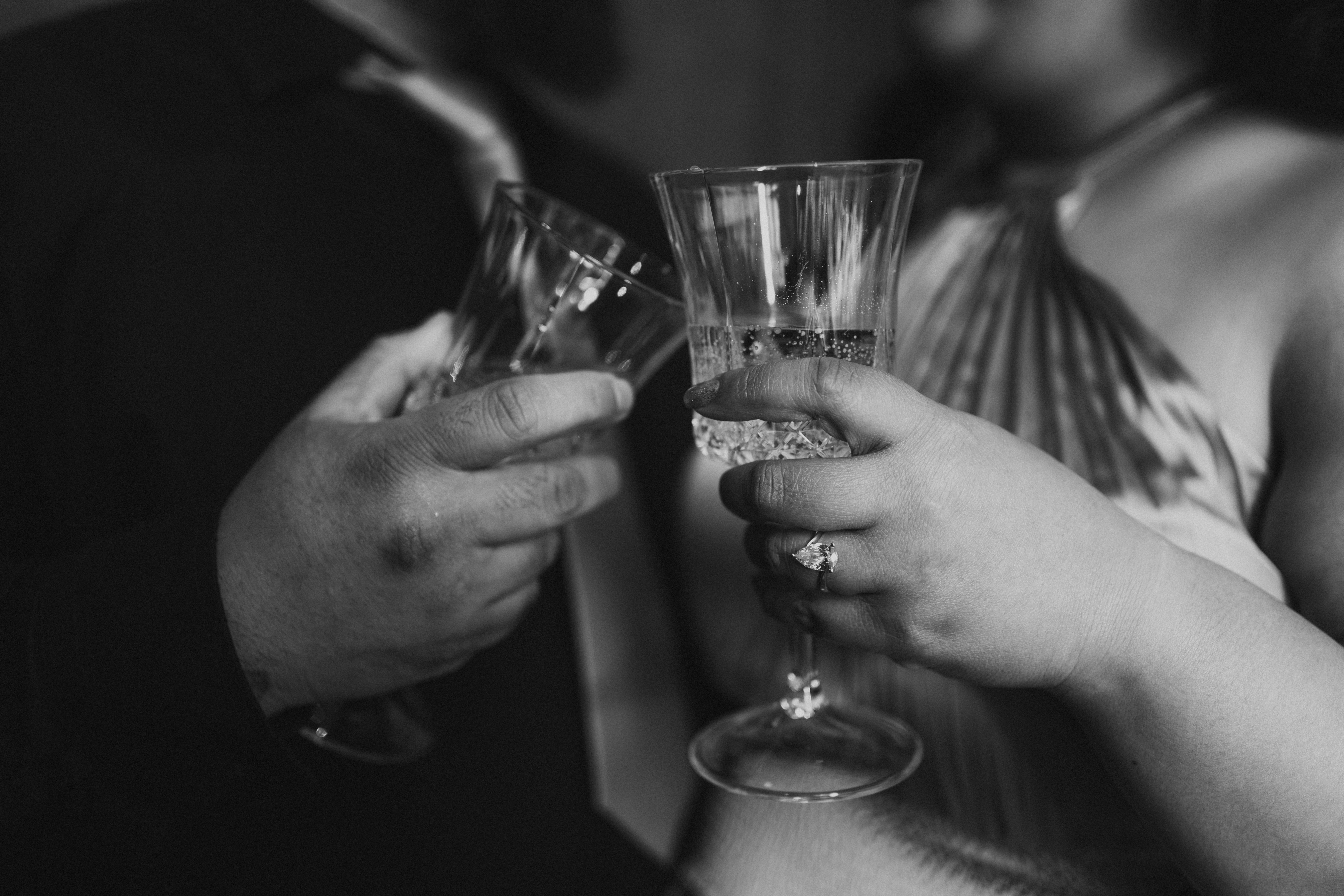 Dre and Judy clinking champagne glasses with engagement ring visible — intimate engagement session at Fort Garry Hotel Winnipeg by Ngo Photography
