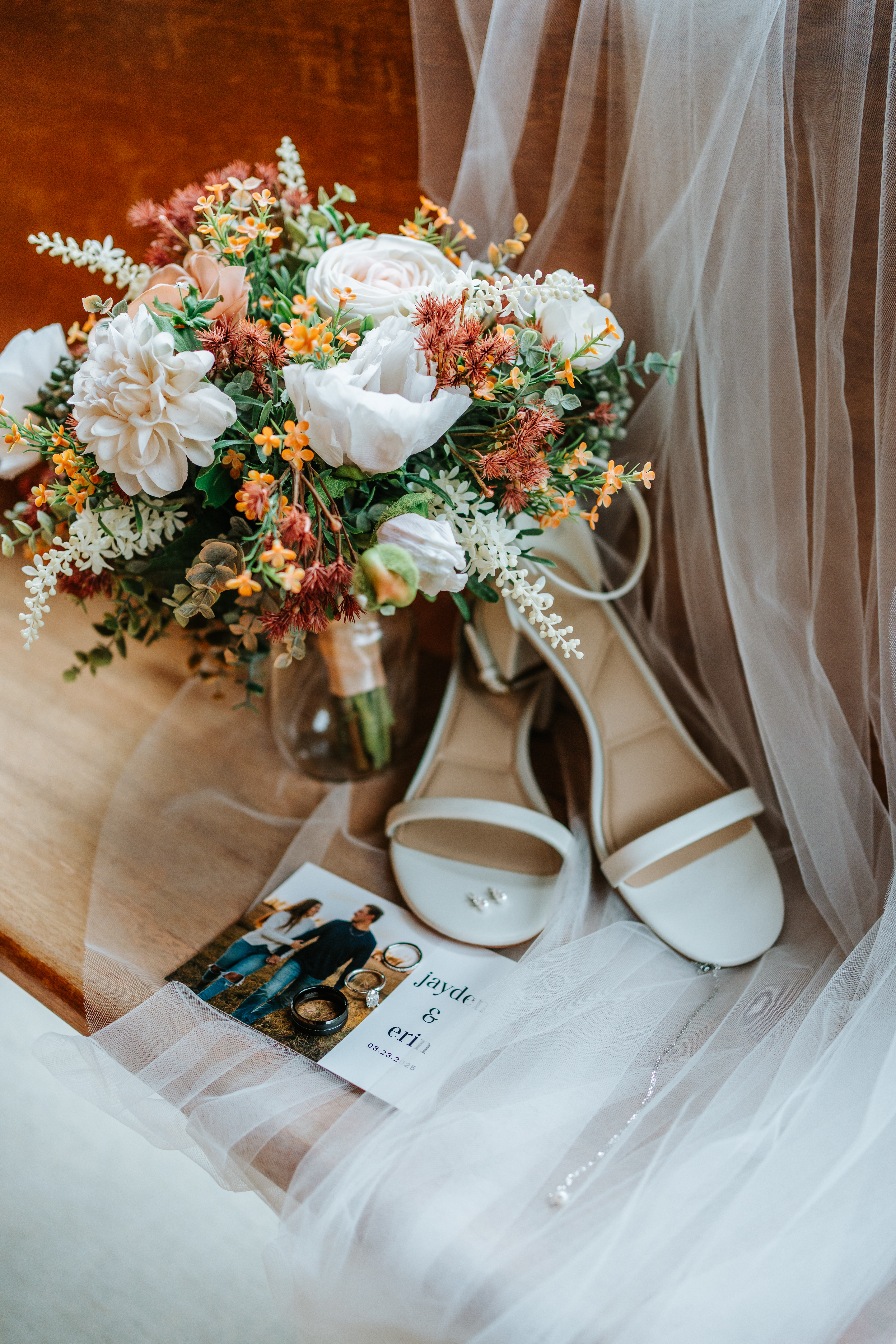 Erin's bridal bouquet with blush peonies and wildflowers beside white sandals and wedding invitation card on veil — Buttercup Café wedding details by Chris Ngo
