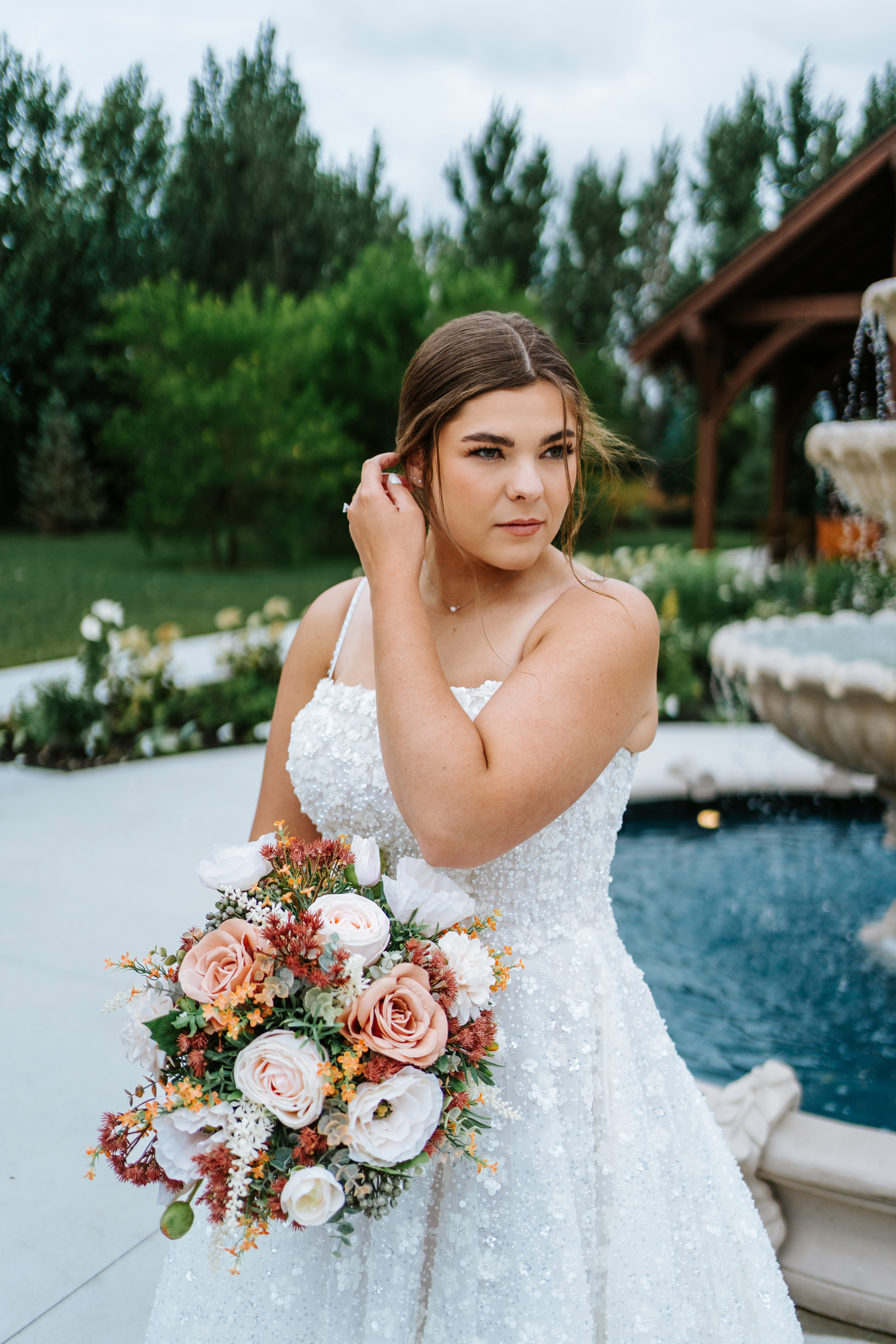 Erin in her sparkle ballgown holding her blush bouquet by the tiered fountain at Buttercup Café Manitoba — bridal portrait by Chris Ngo Ngo Photography