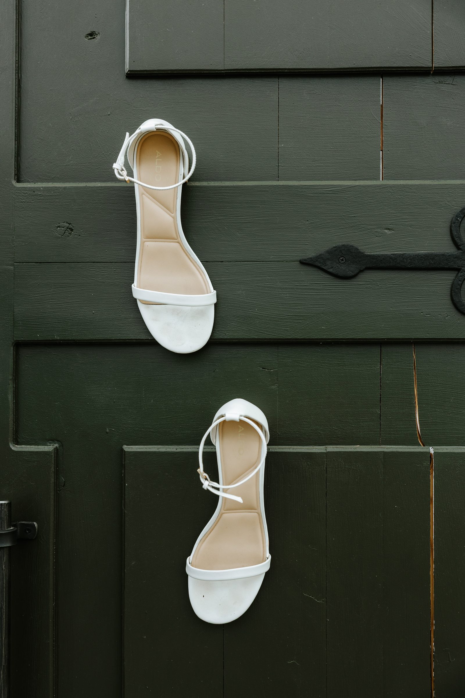 Erin's minimalist white bridal sandals against the dark green door at Buttercup Café Manitoba — wedding detail photography by Chris Ngo