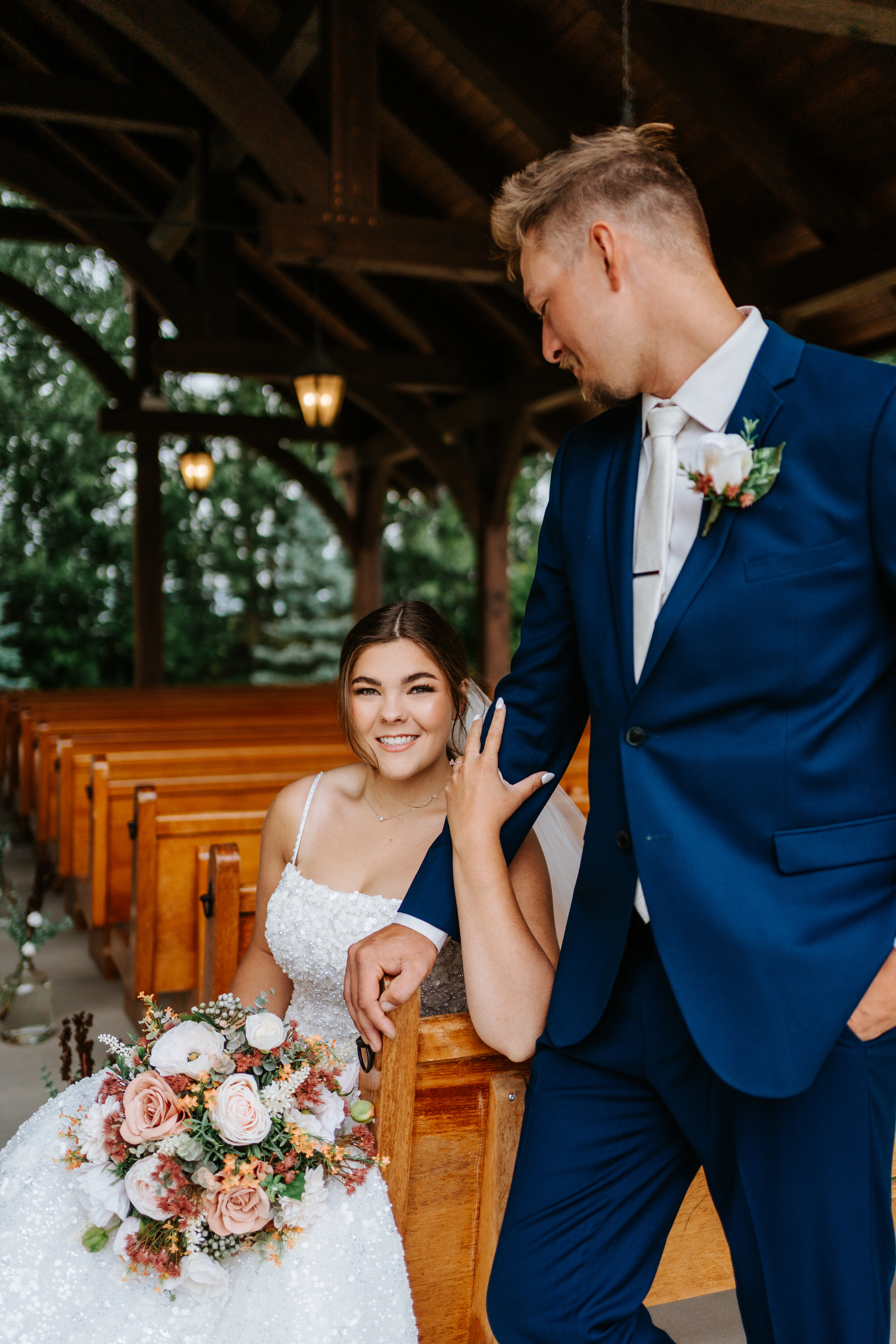 Erin and Jayden in the wooden pews of the timber pavilion at Buttercup Café — intimate couple portrait by Chris Ngo Winnipeg wedding photographer
