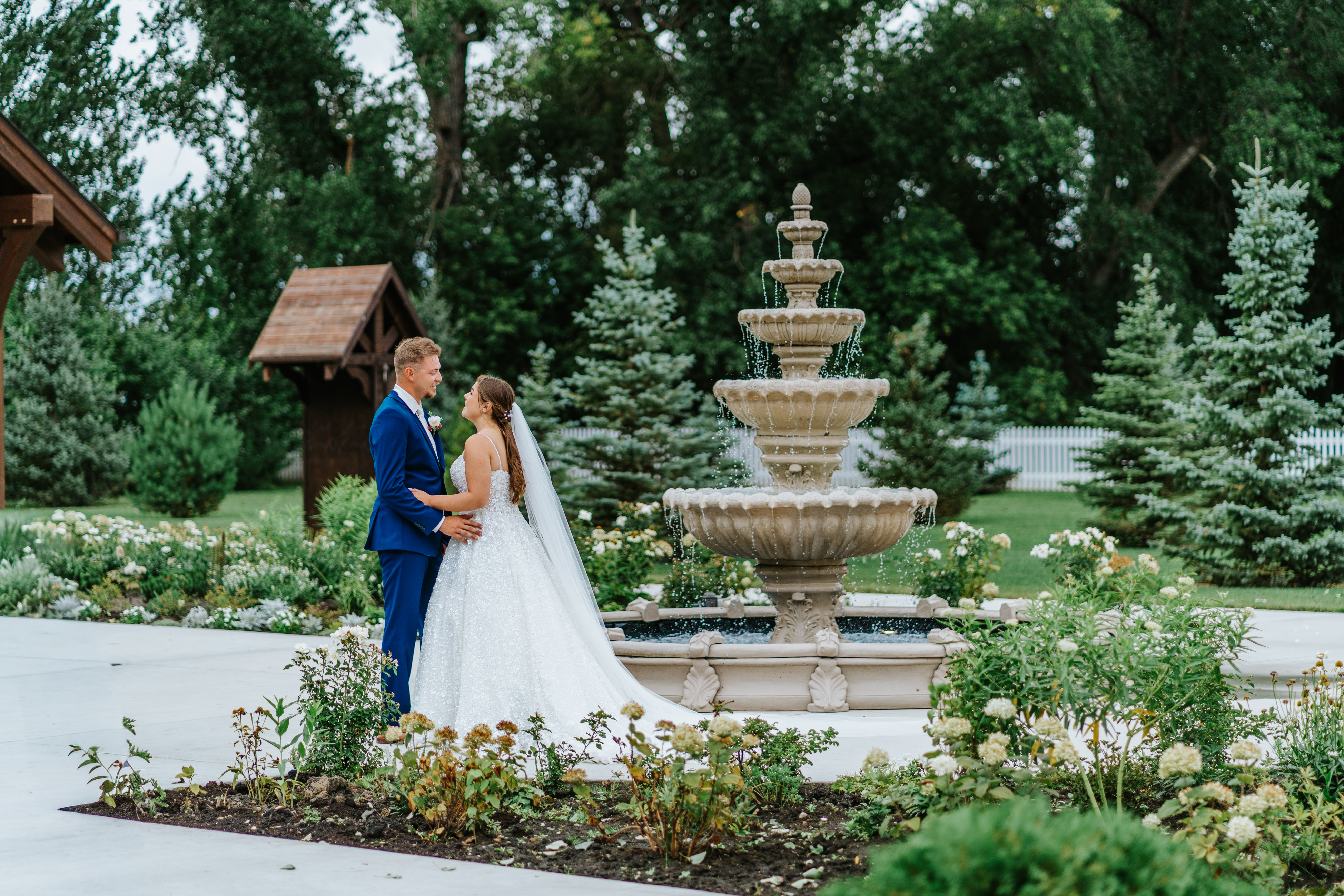 Erin and Jayden portrait in front of the tiered fountain surrounded by rose gardens at Buttercup Café Manitoba — couple portrait by Chris Ngo