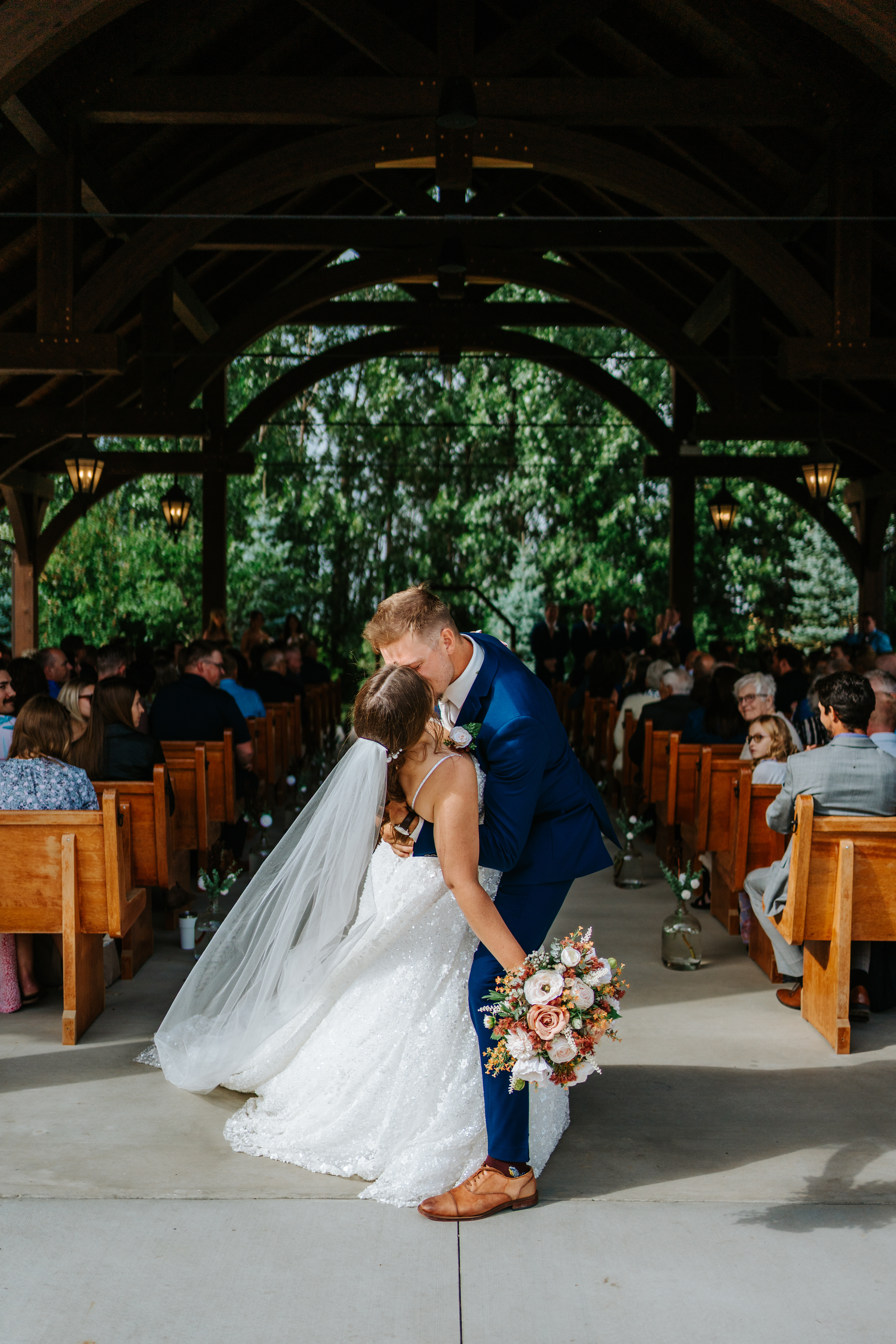 Jayden dipping Erin for a kiss at the altar in the timber pavilion at Buttercup Café Manitoba — joyful ceremony moment by Chris Ngo Ngo Photography
