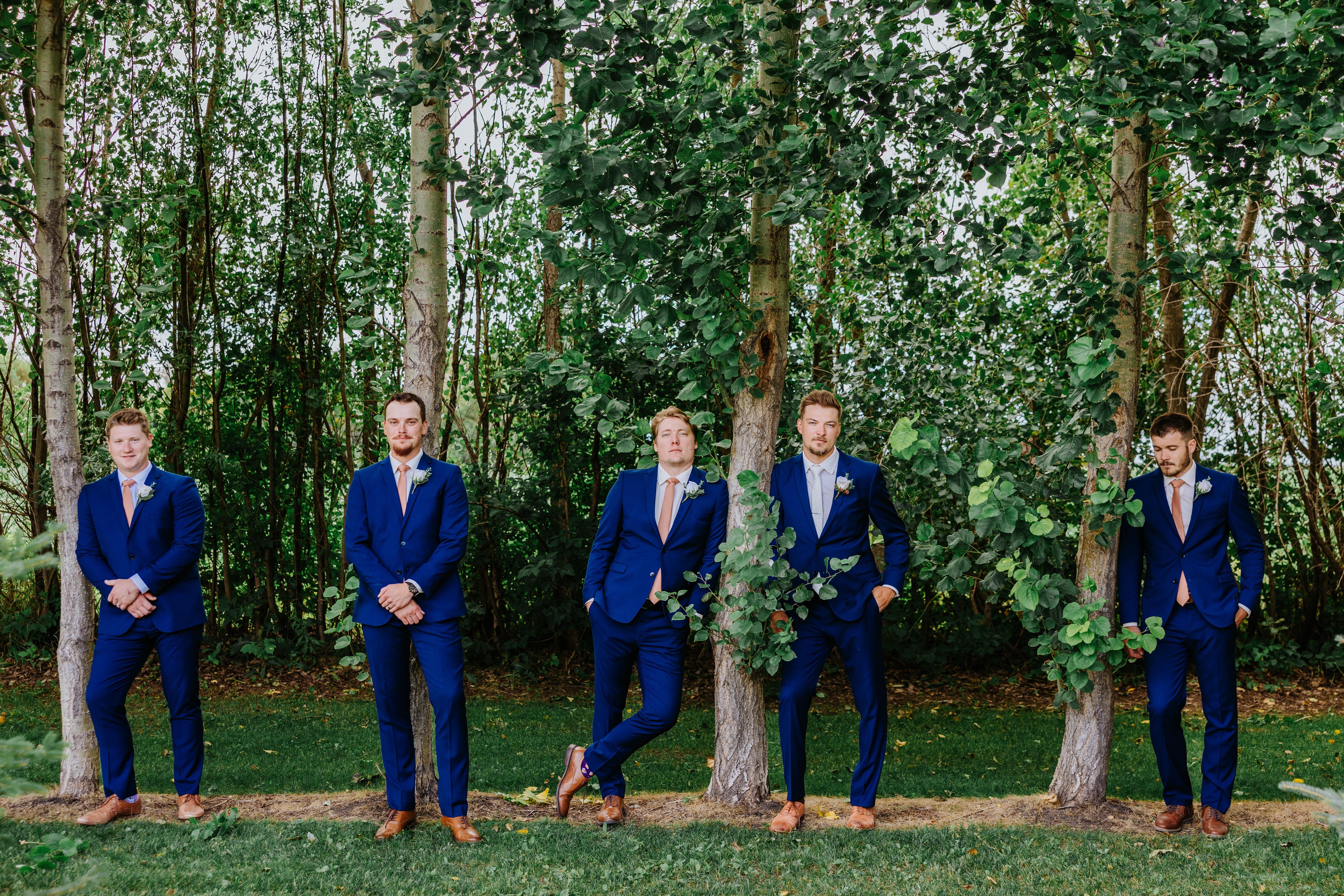 Jayden and his groomsmen in navy suits leaning against poplar trees at Buttercup Café Manitoba — groomsmen portrait by Chris Ngo Ngo Photography