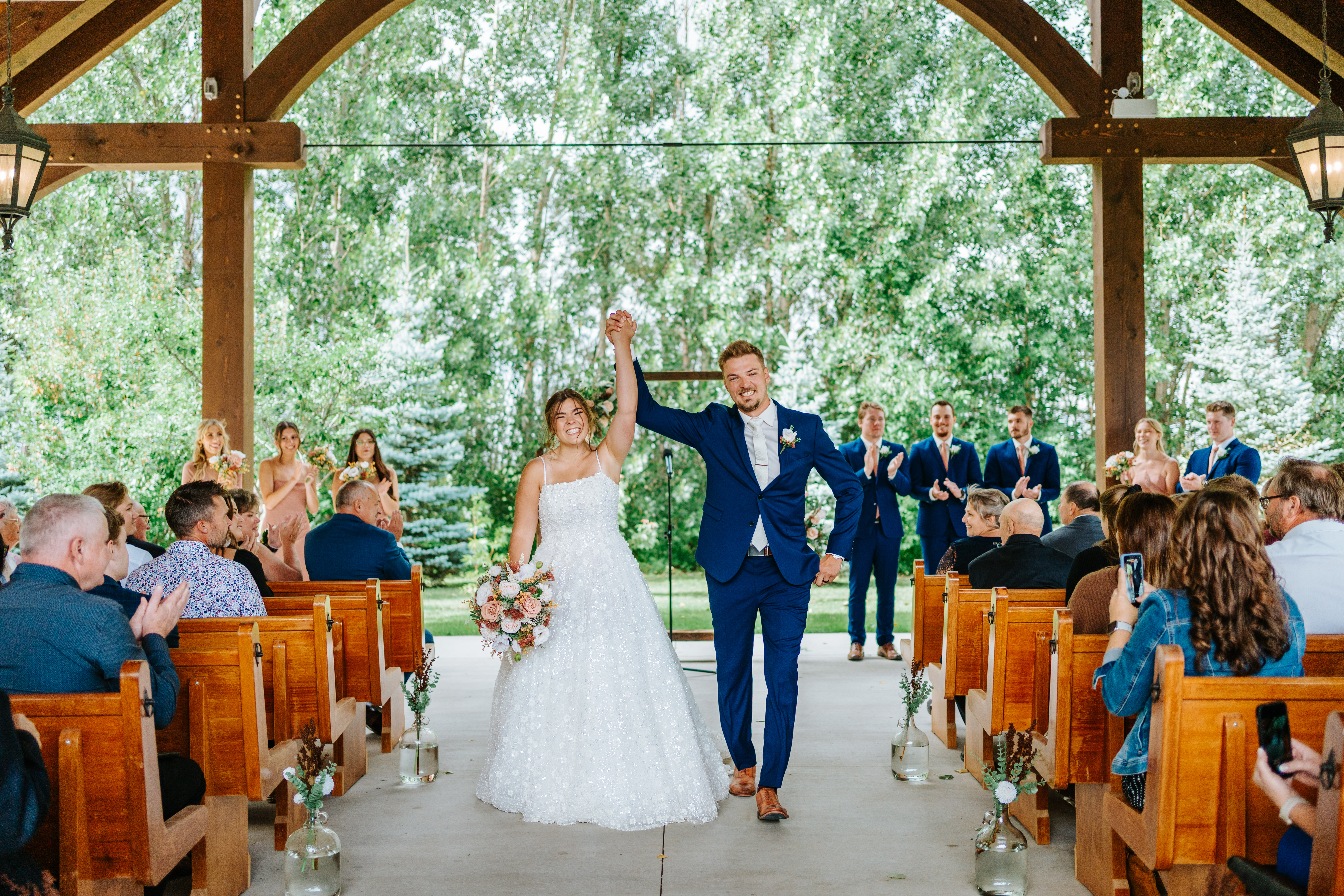 Erin and Jayden raising their hands joyfully as they walk back down the aisle at Buttercup Café — recessional wedding photography by Ngo Photography Winnipeg