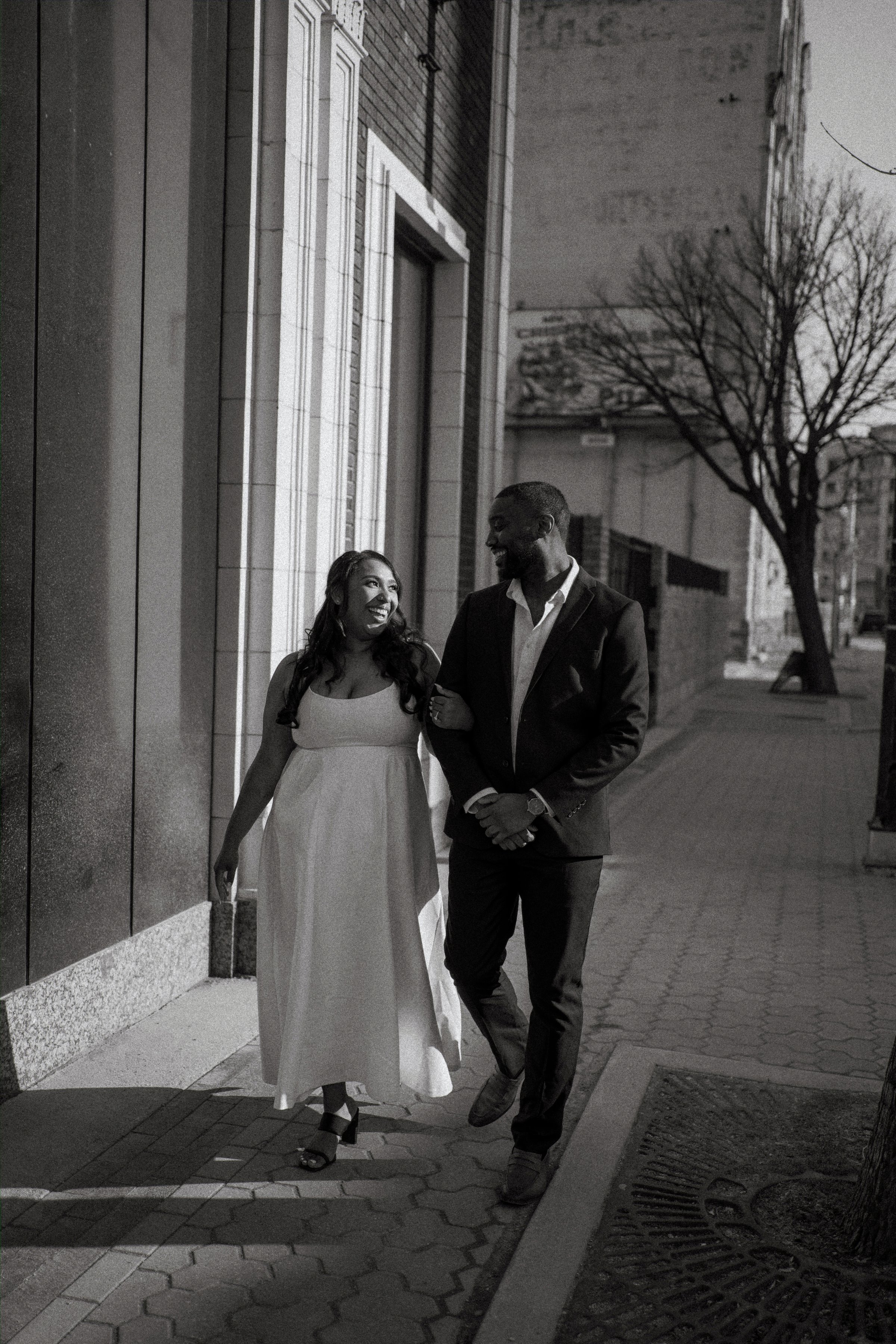 Jaida and Jordan on the top level of a downtown Winnipeg parkade at golden hour with the city skyline behind them — engagement photography by Ngo Photography
