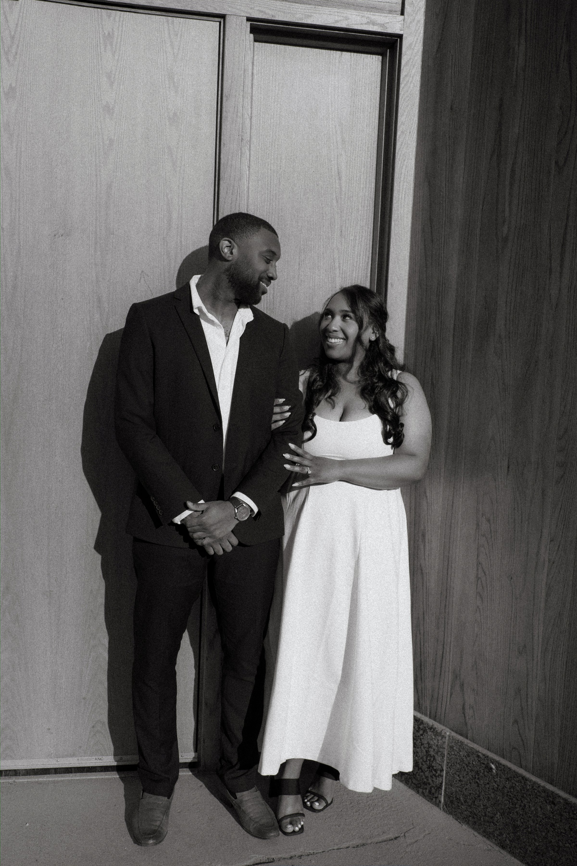 Jaida and Jordan embracing at golden hour on a Winnipeg parkade rooftop — downtown engagement photography by Chris Ngo