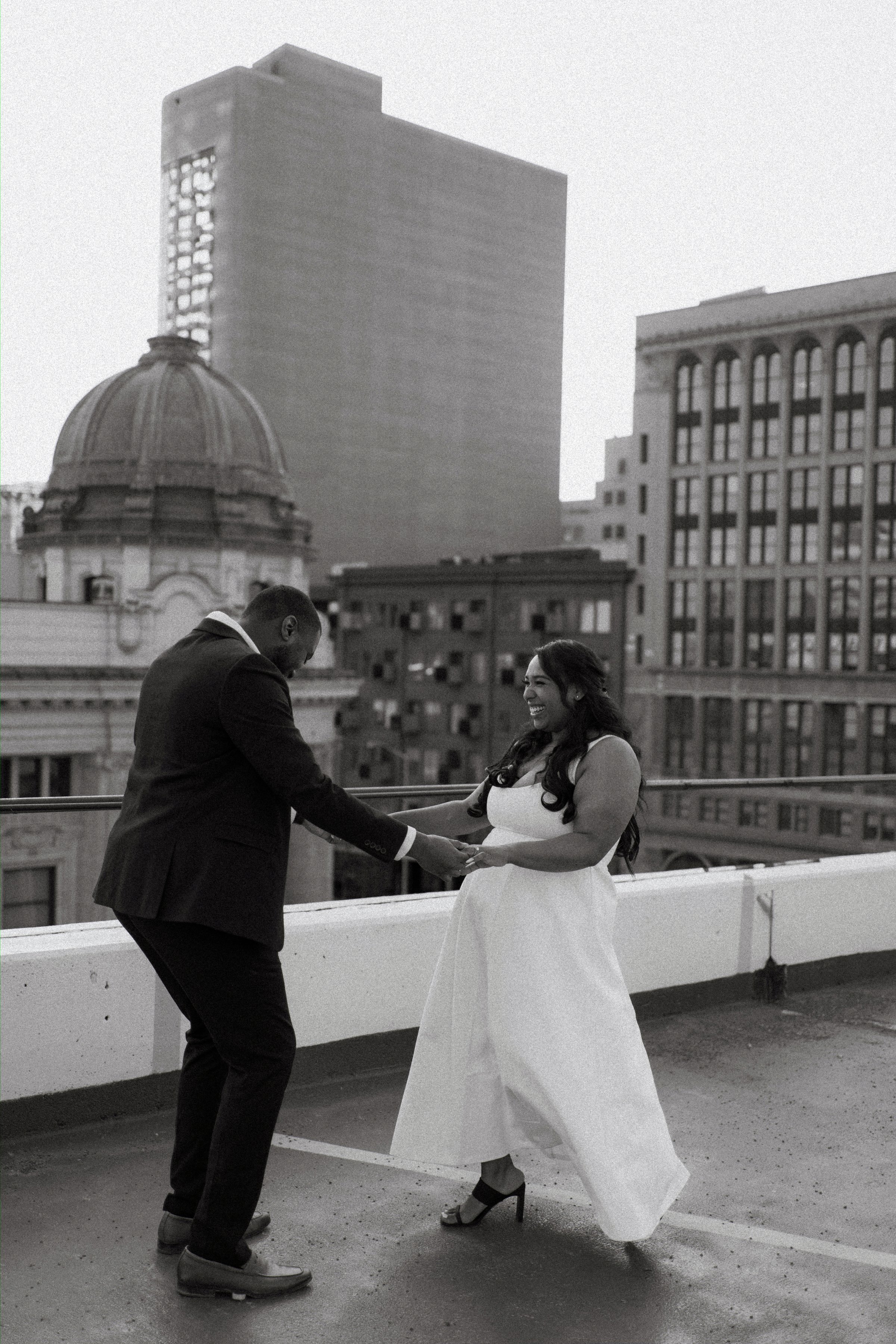 Wide golden hour shot of Jaida and Jordan on the top level of a Winnipeg parkade with warm sunset sky — engagement photography by Chris Ngo Ngo Photography
