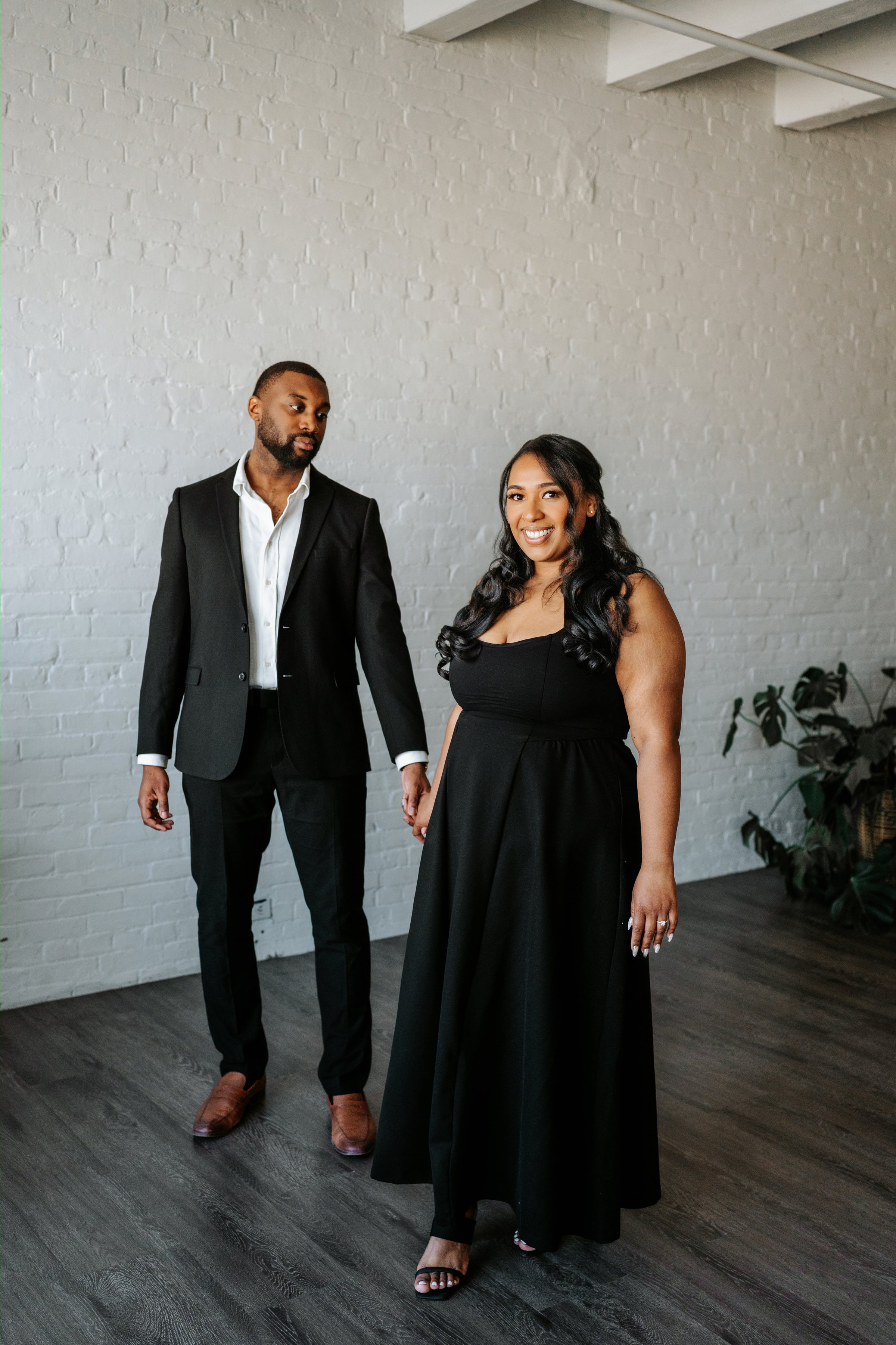 Jaida and Jordan walking on a wide Exchange District sidewalk Winnipeg — engagement photography by Ngo Photography