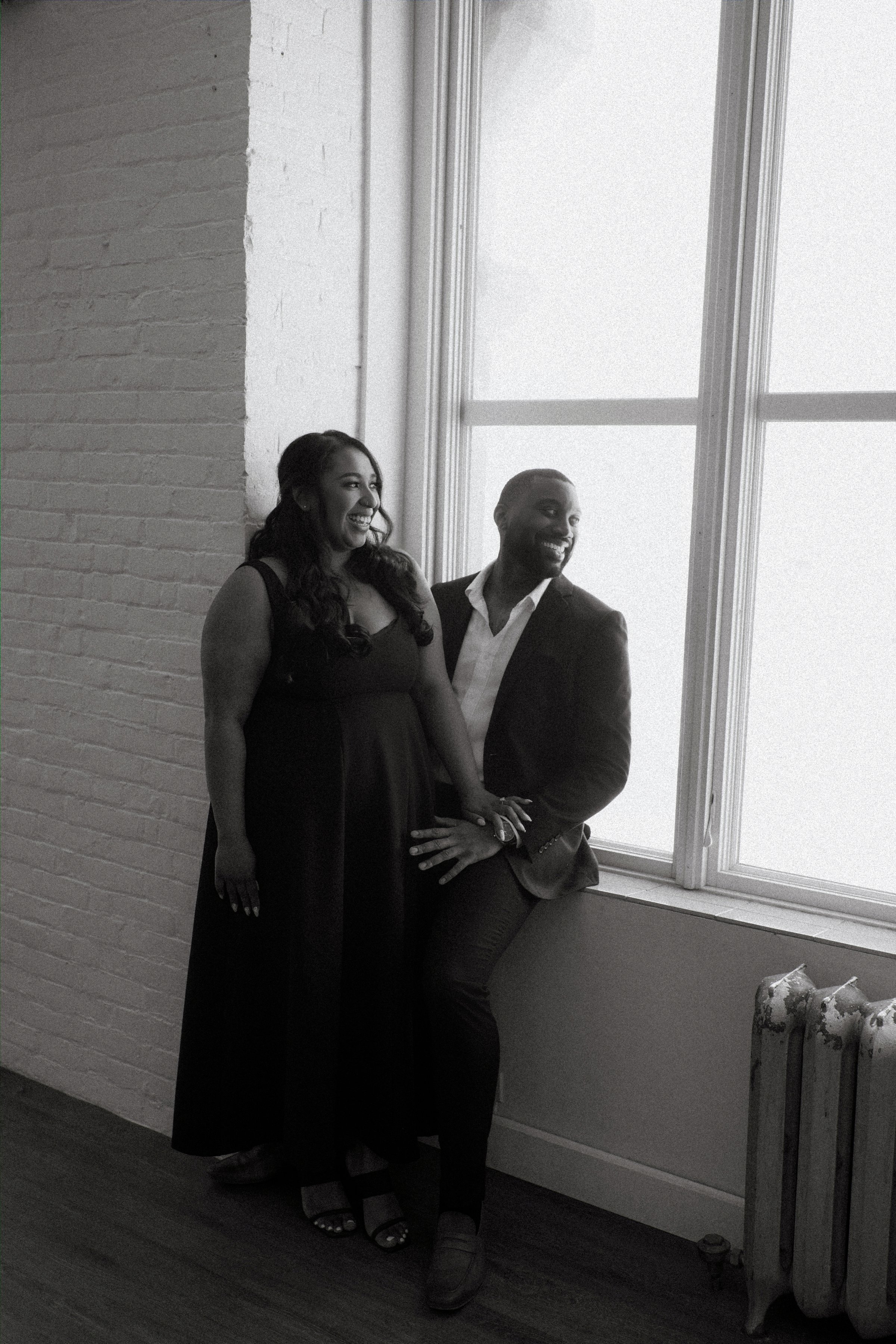 Wide street shot of Jaida and Jordan in downtown Winnipeg's Exchange District with heritage facades — engagement photography by Chris Ngo