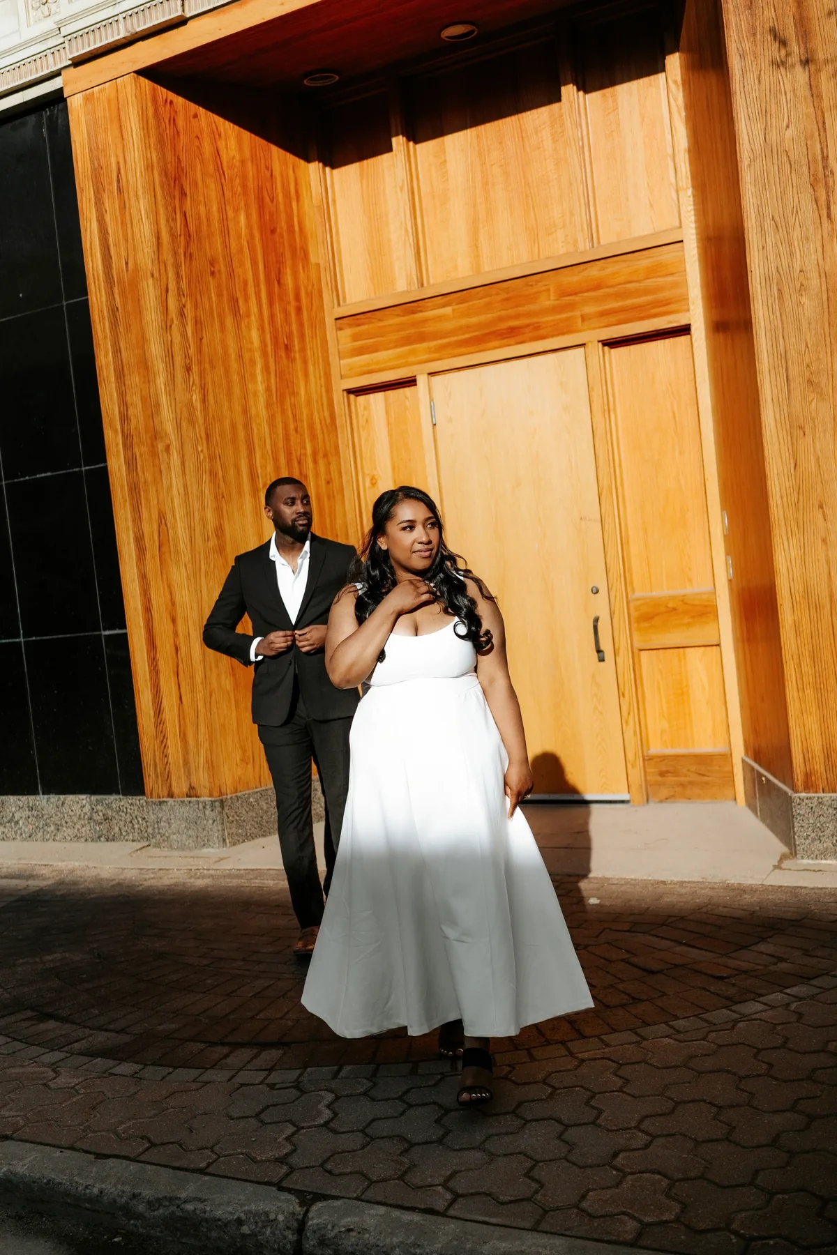 Jaida leading Jordan through the CMHR exterior, bride in white dress and groom in dark suit — Winnipeg wedding photography by Ngo Photography