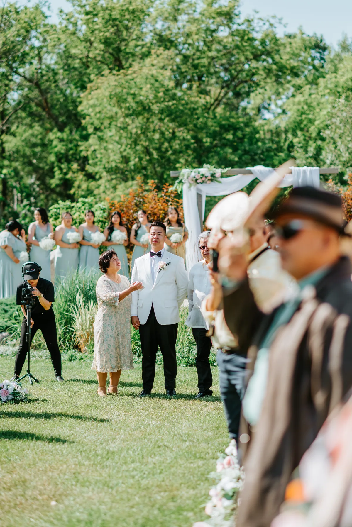 Wide shot of Jay walking the aisle with guests on either side at Hawthorne Estates outdoor ceremony, Manitoba