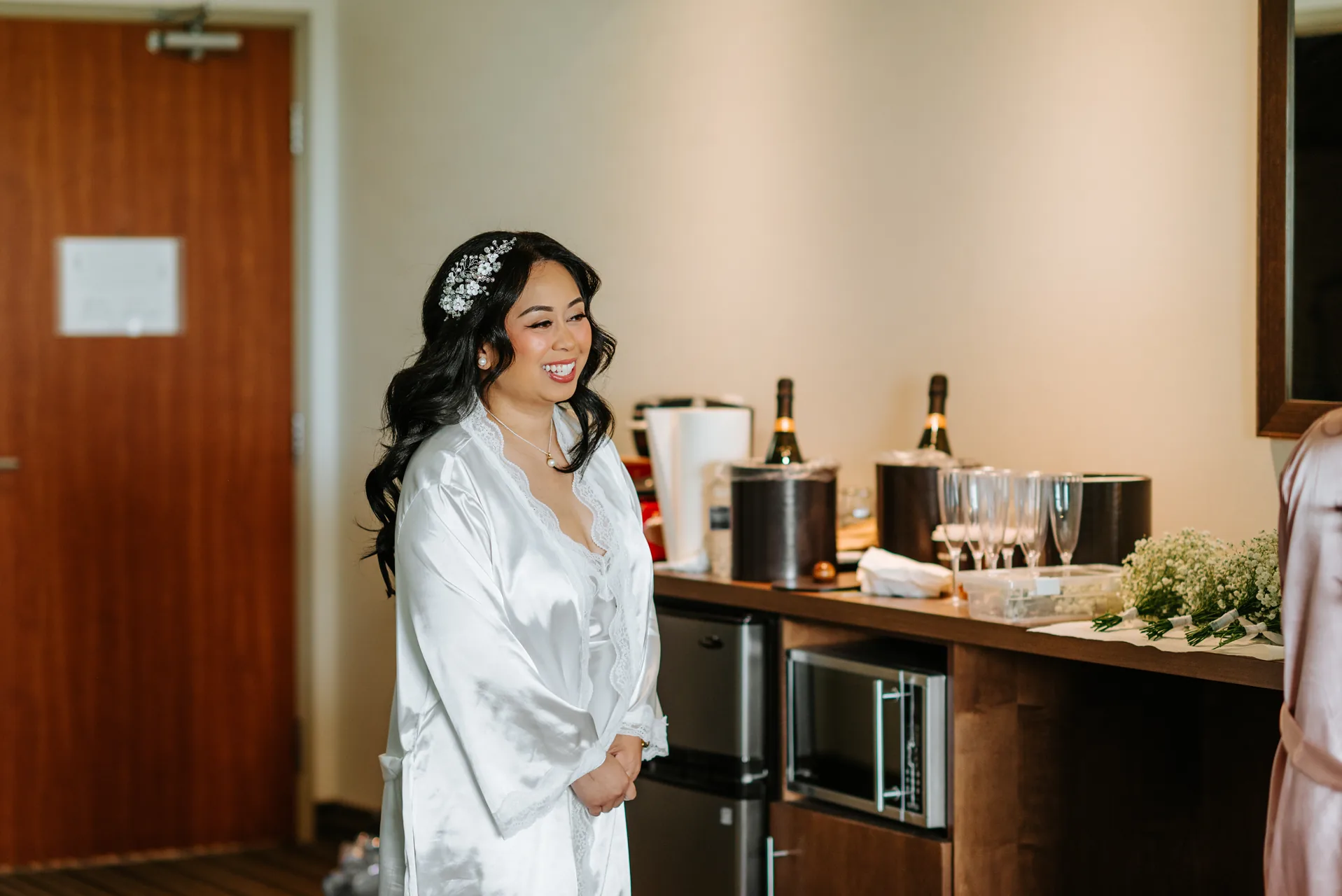Jay getting ready in her white satin robe with champagne setup in the background — Hawthorne Estates wedding, Manitoba