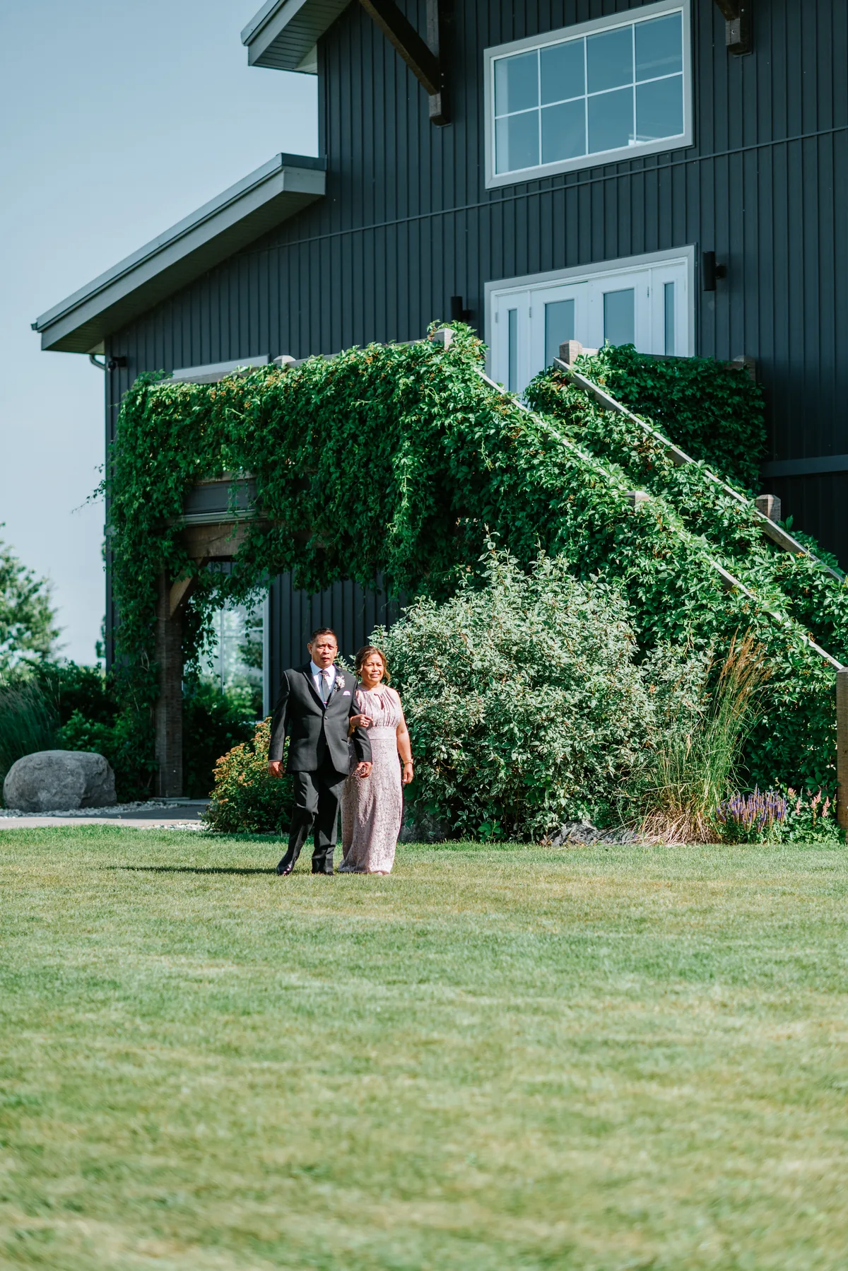 Jay walking the aisle toward the ceremony with the Hawthorne Estates barn in the background, Manitoba