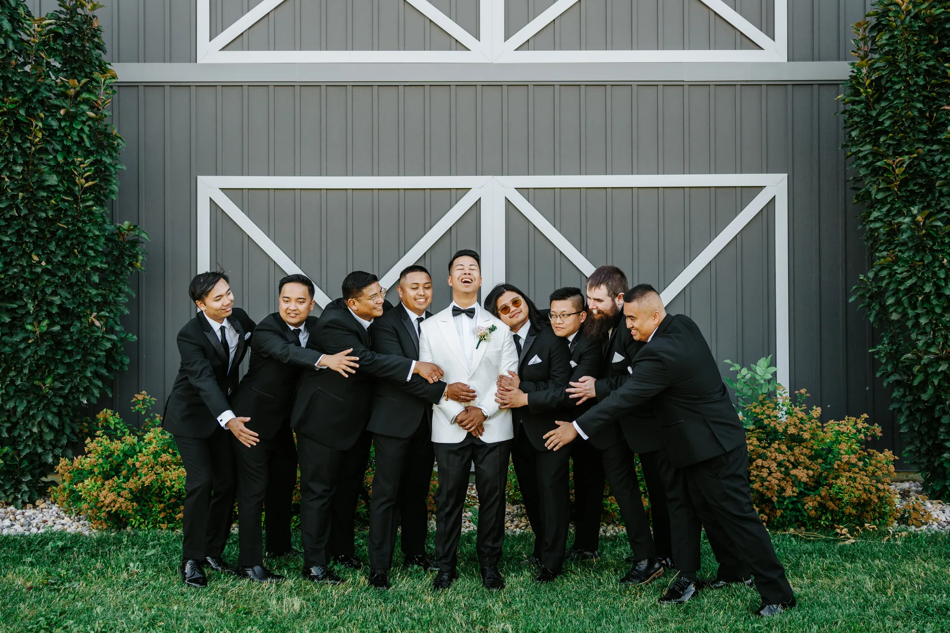 Bridesmaids portrait in sage gowns in front of the Hawthorne Estates barn exterior, Manitoba