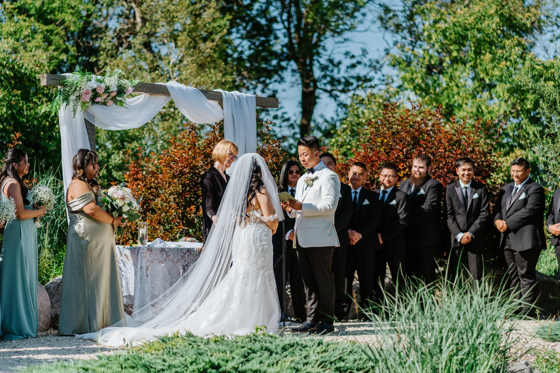 Jay and Mark exchanging vows with full bridal party at Hawthorne Estates outdoor ceremony — colour, Manitoba